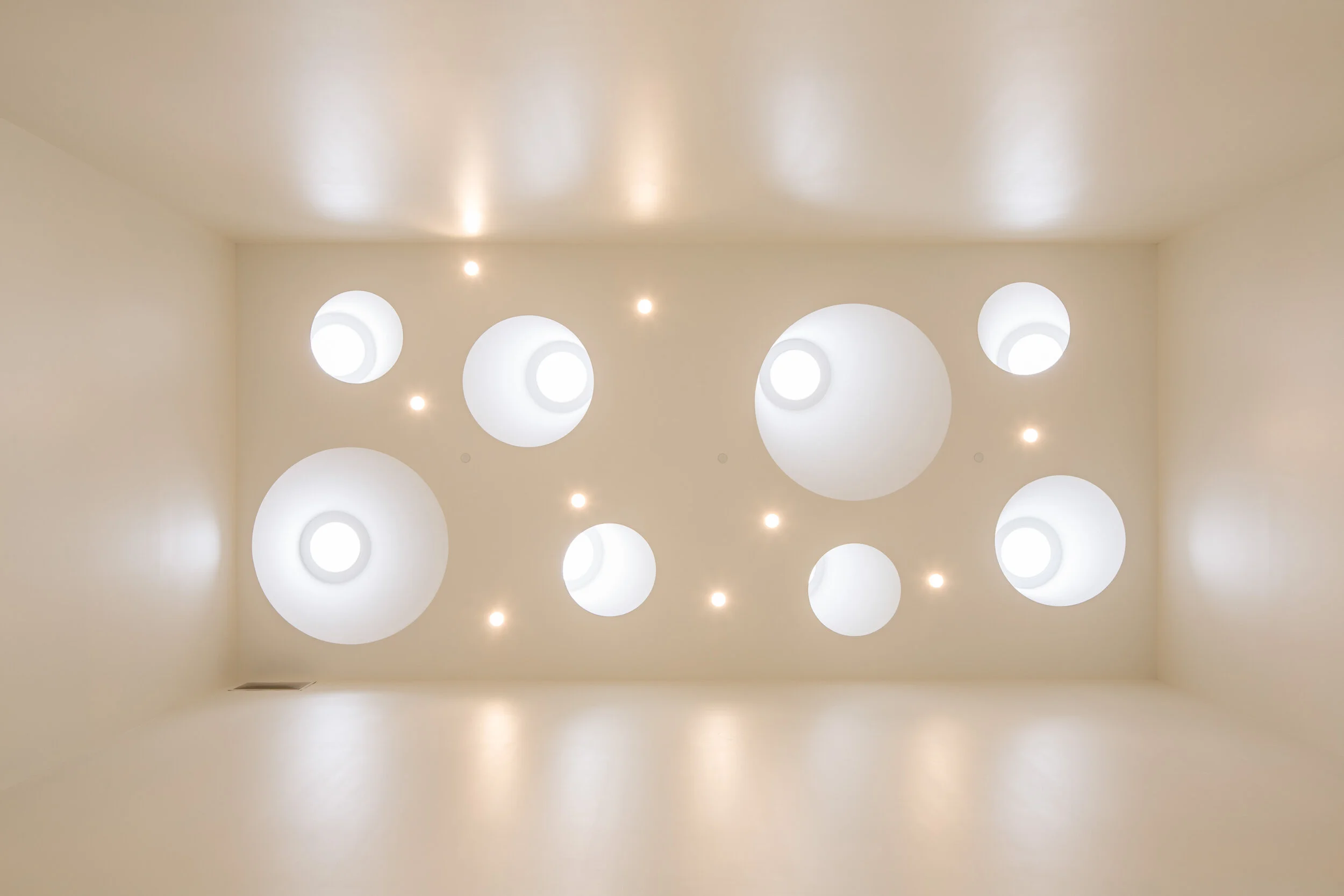 Circular light wells above illuminate a grand stairwell below.