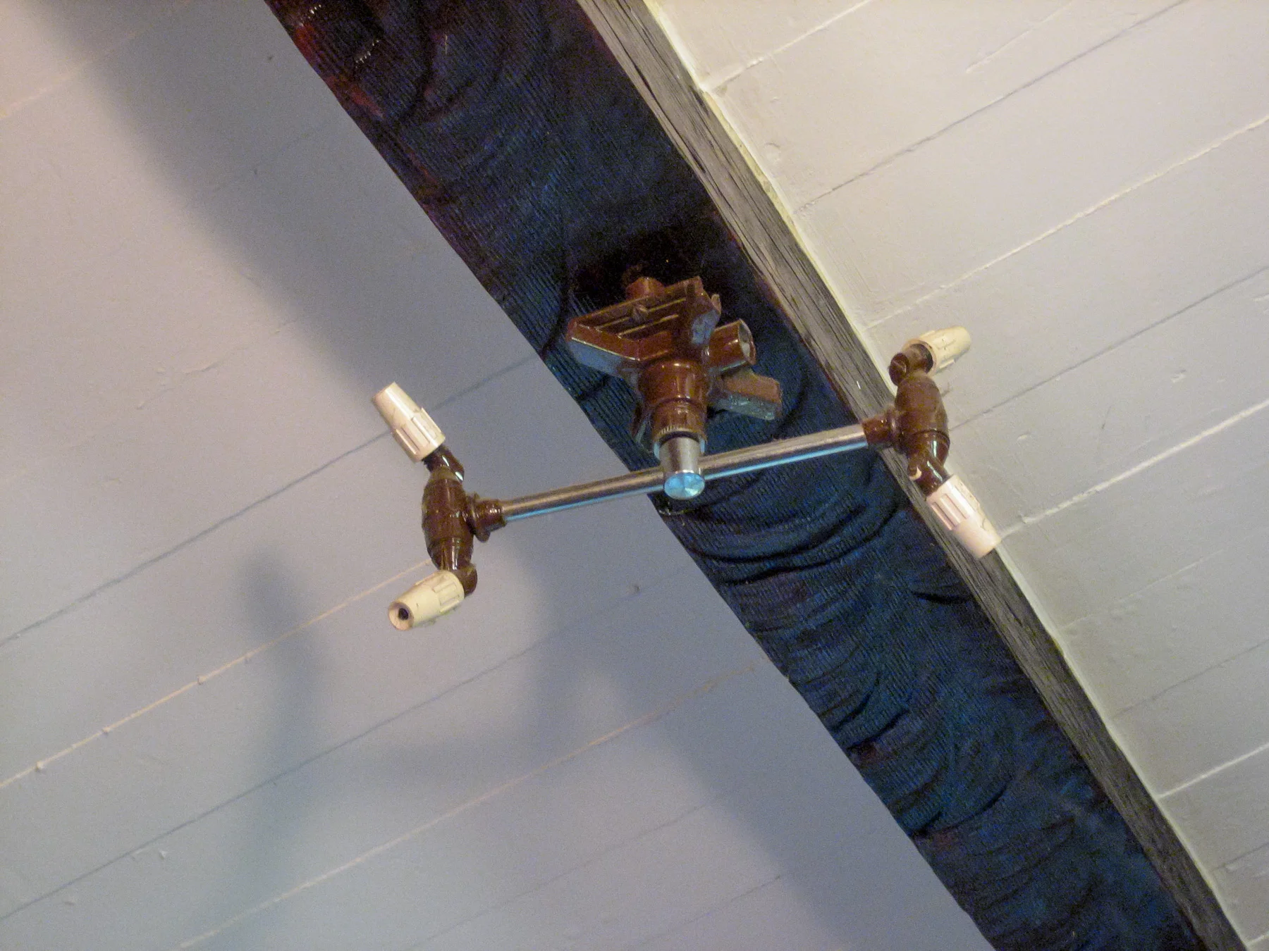 Sprinkler head in the ceiling of the living room. A drain is located below and all of the furnishings are plastic covered and waterproof.