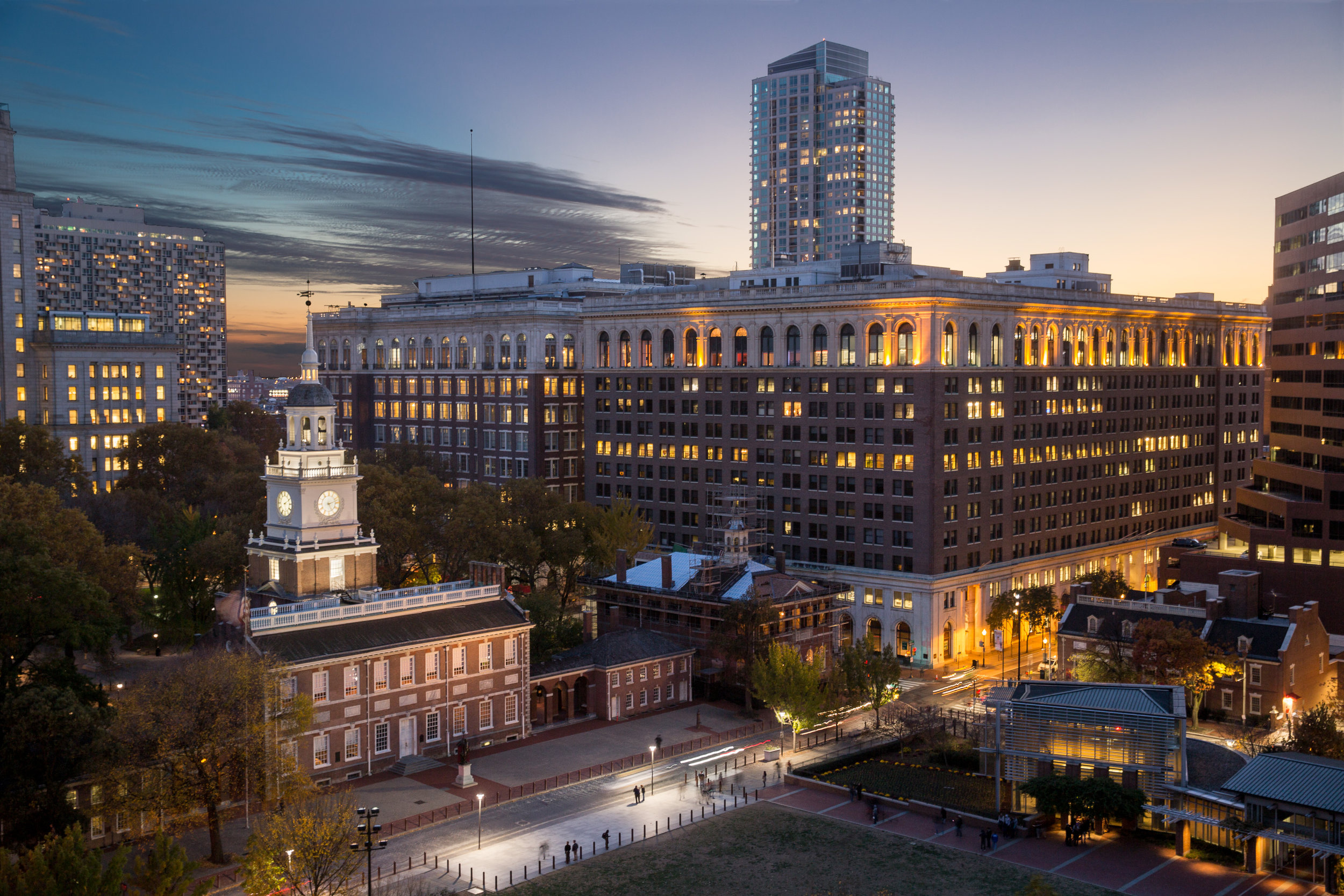 This Philadelphia twilight view shows the proximity of Public Ledger Building’s (12 story building on right) to world famous Independence Hall with the steeple.