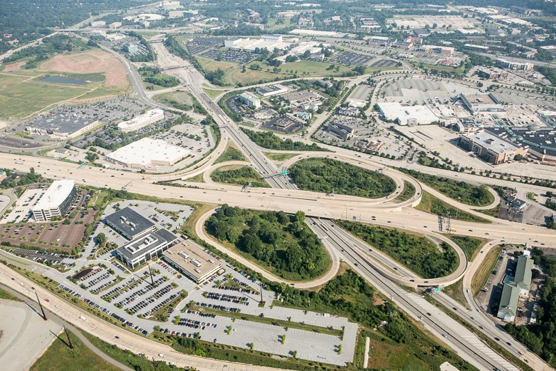 A wide view from above highlights suburban America’s highways, shopping malls, and office buildings.