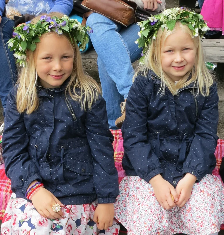 Young Swedish girls with garlands in their hair at a daytime Midsommer celebration.
