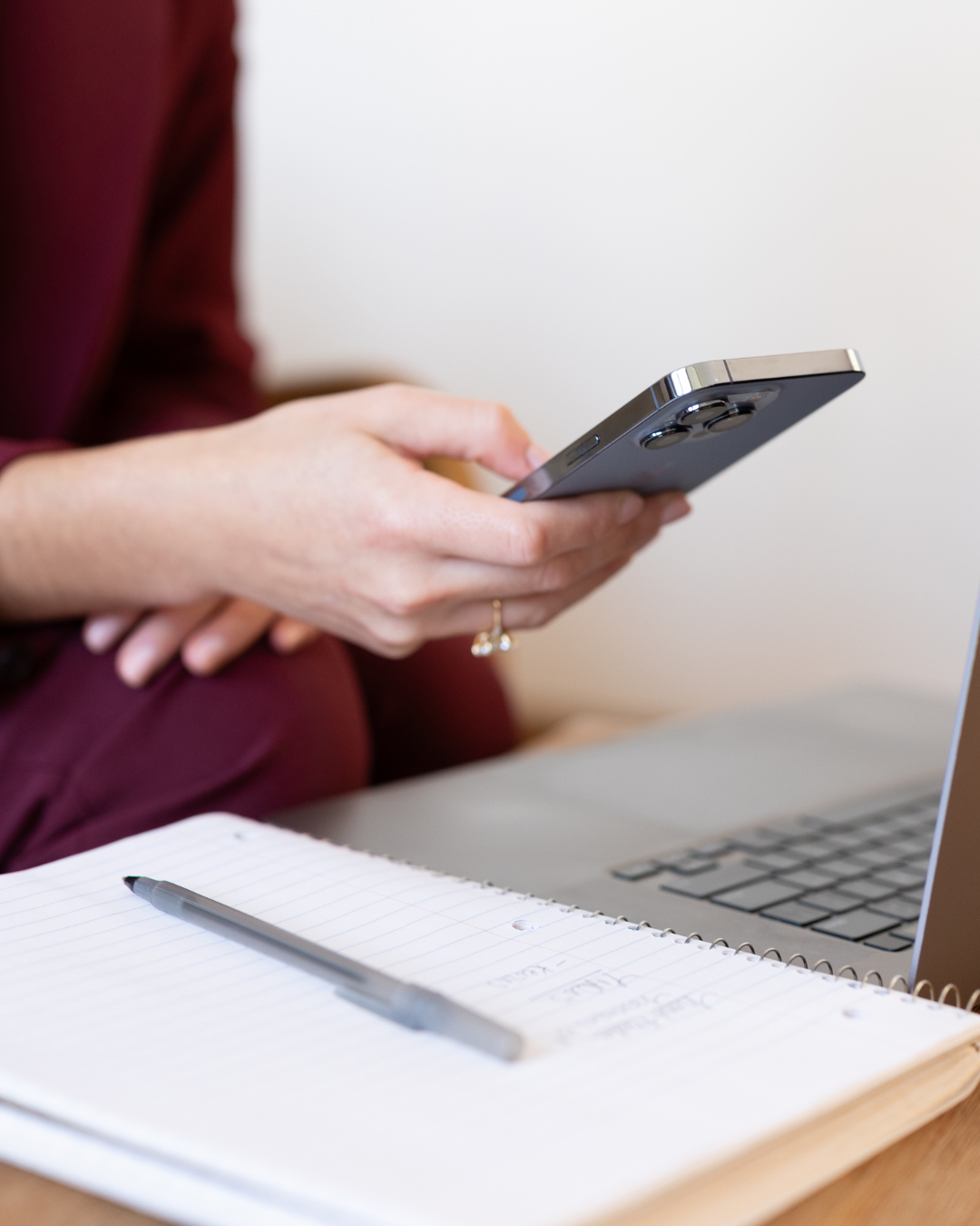 A photo of Nina Russo of Nina Media holding a blue iPhone over a laptop and notebook.