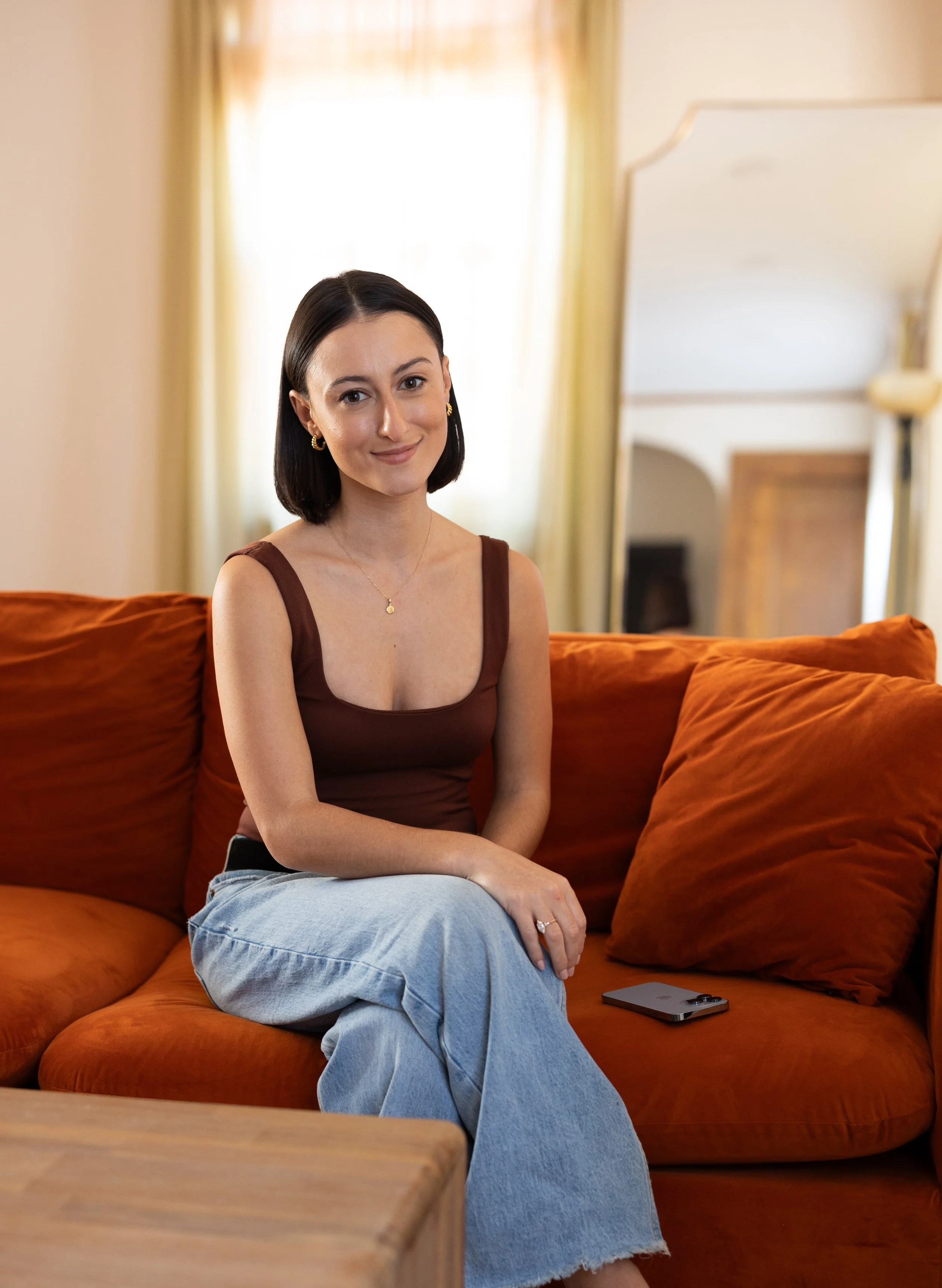 Nina Russo of Nina Media sitting on an orange couch.