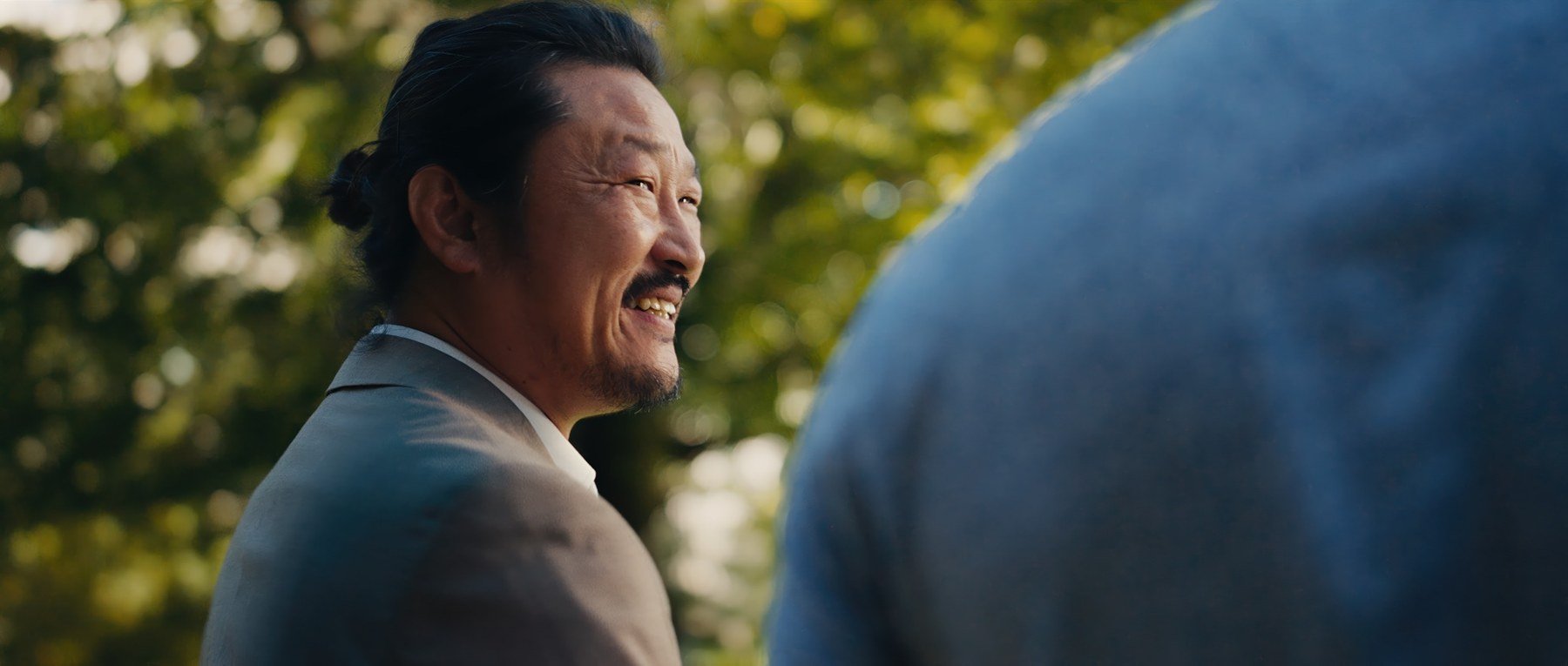 Pedigree short film still — Kai Wen Hu - Samuel smiles while selling in the park.