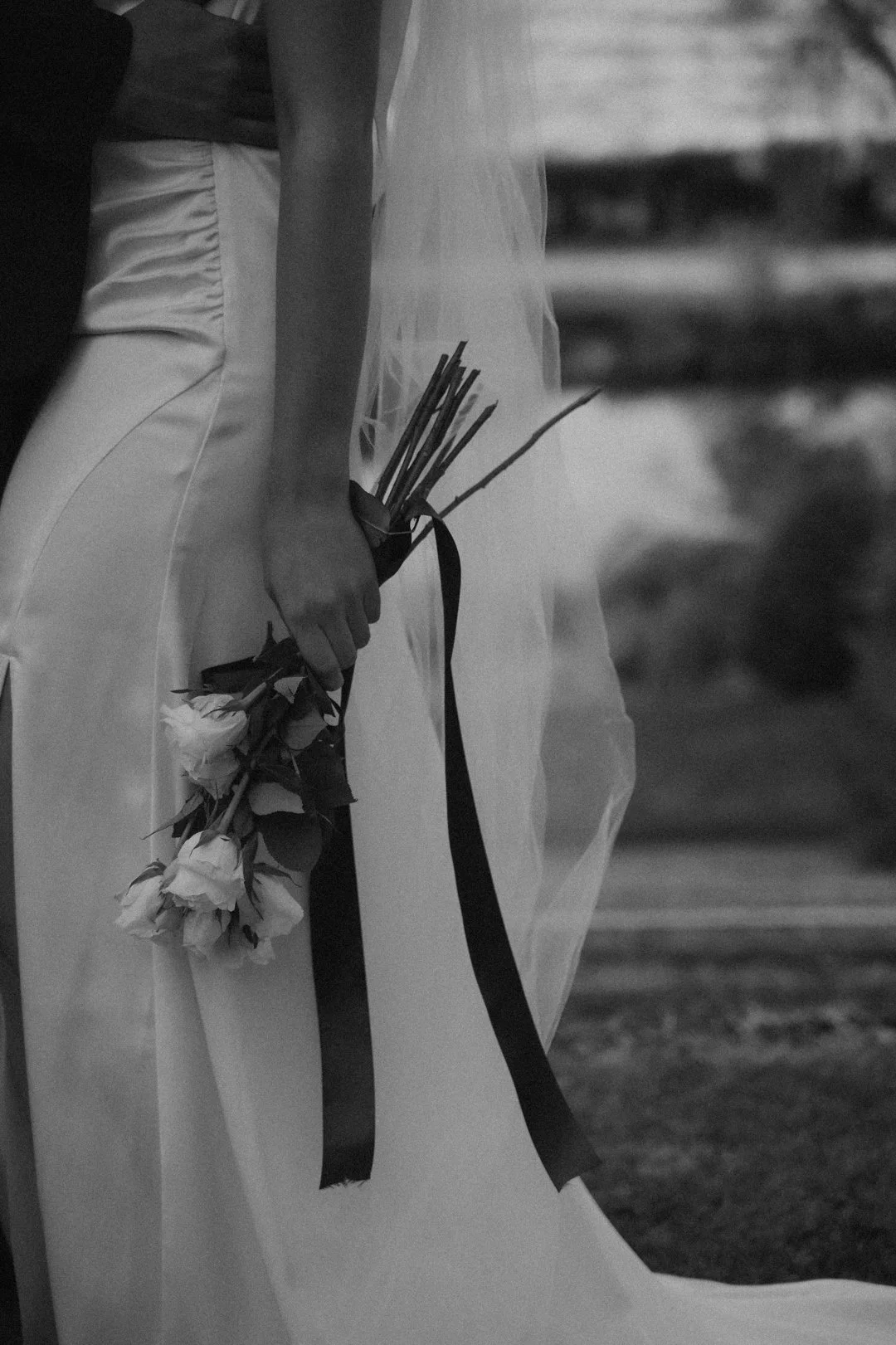 A person in wedding attire holding a bouquet of flowers, with only part of their body visible.