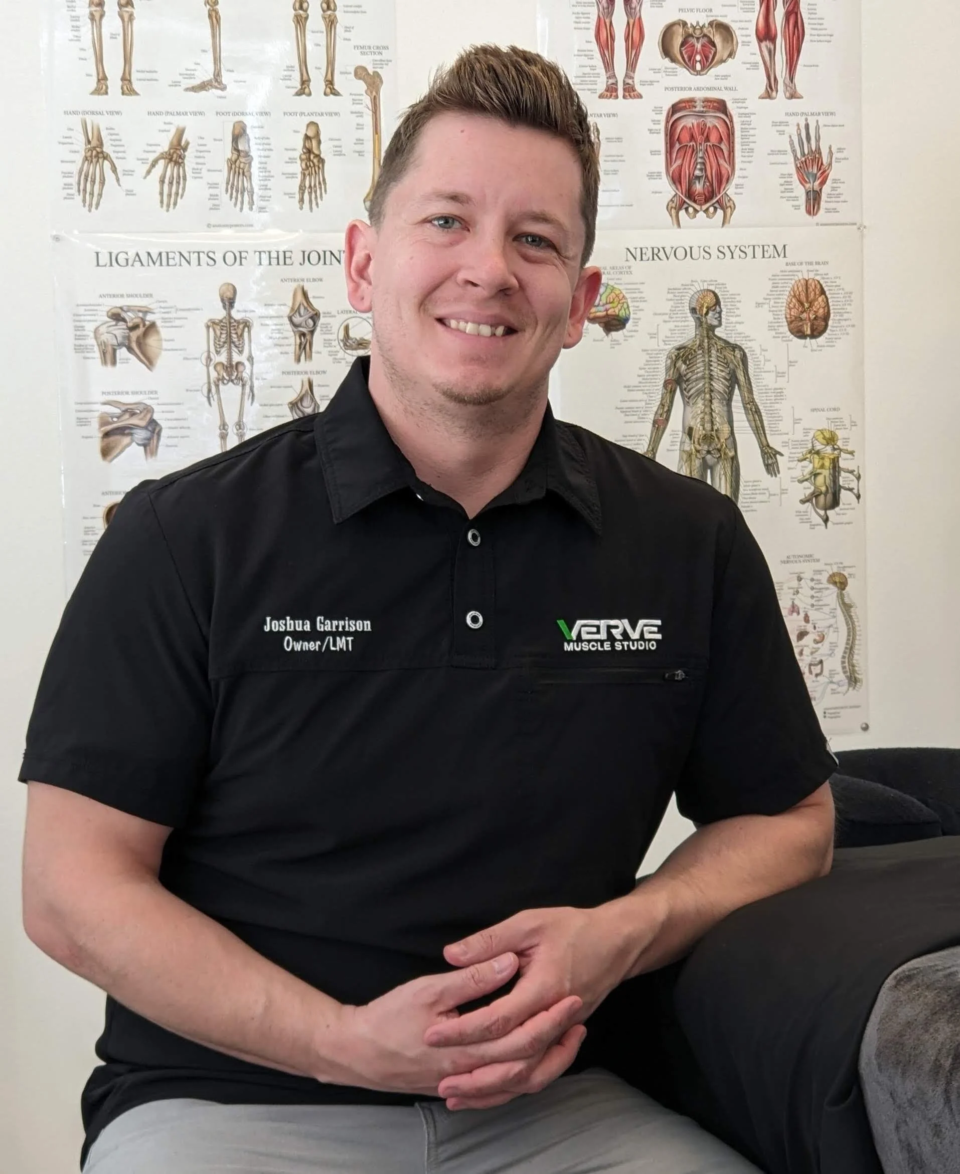 Owner and Therapist posing in front of anatomy diagrams