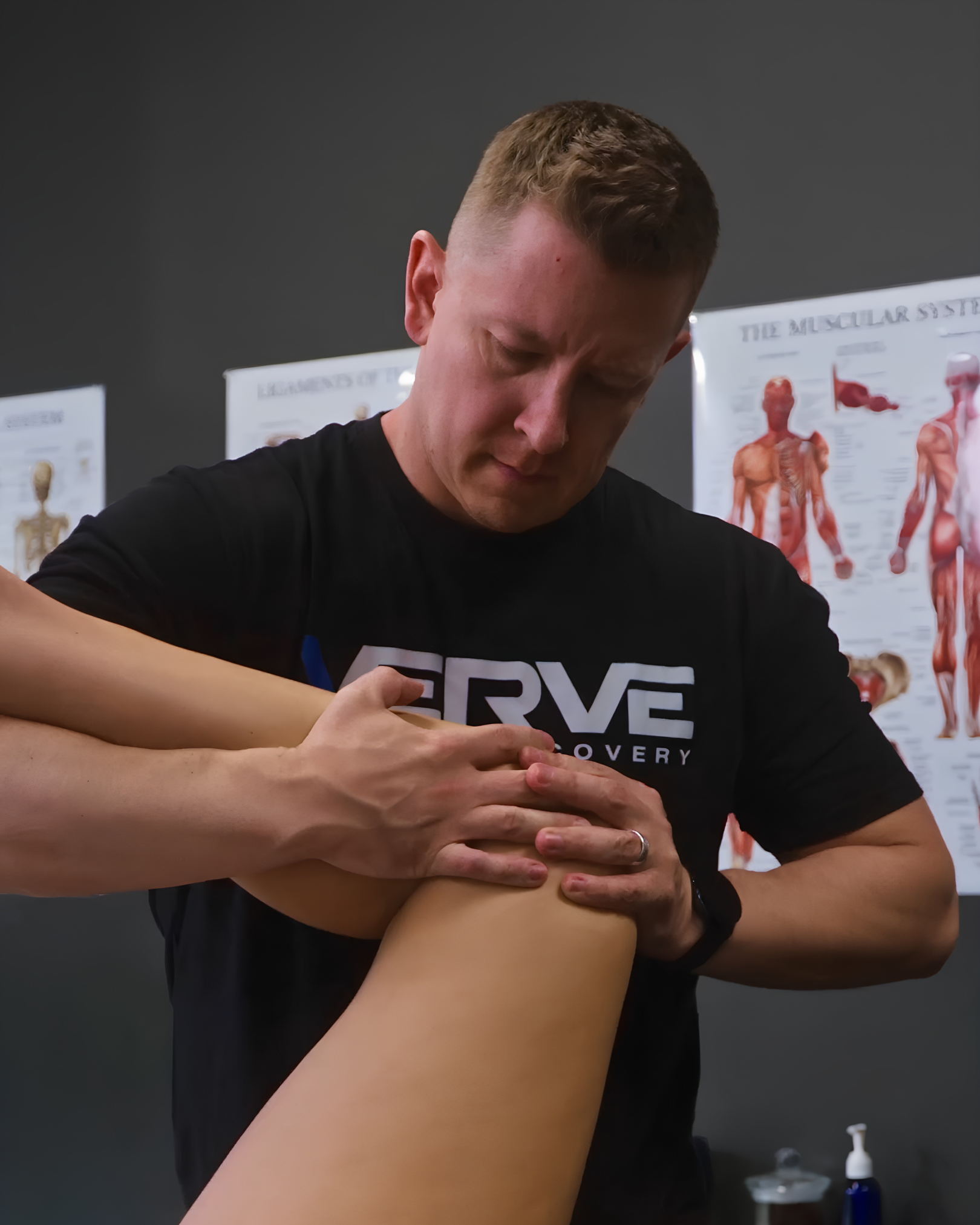 A male Massage Therapist is performing manual therapy on a female patient's back in a clinical setting.