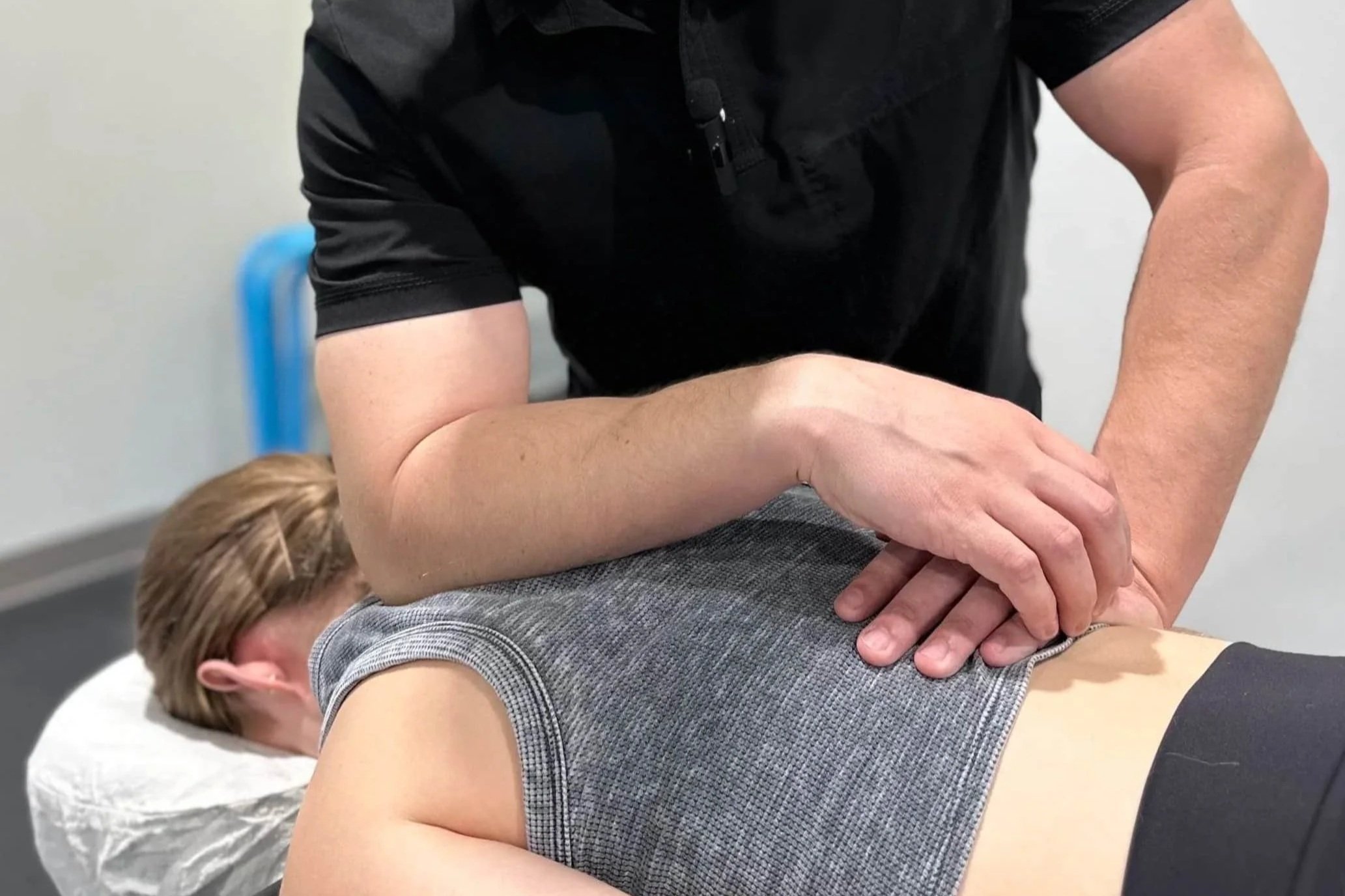 Man performing a chiropractic adjustment or massage on a woman lying face down on a treatment table.