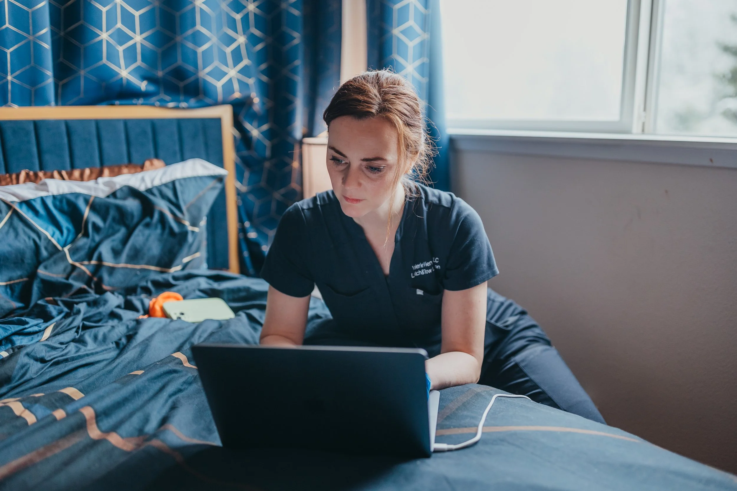 Group of nine women sitting on a staircase, smiling and hugging each other, with some women wearing denim jackets and black or ripped pants.