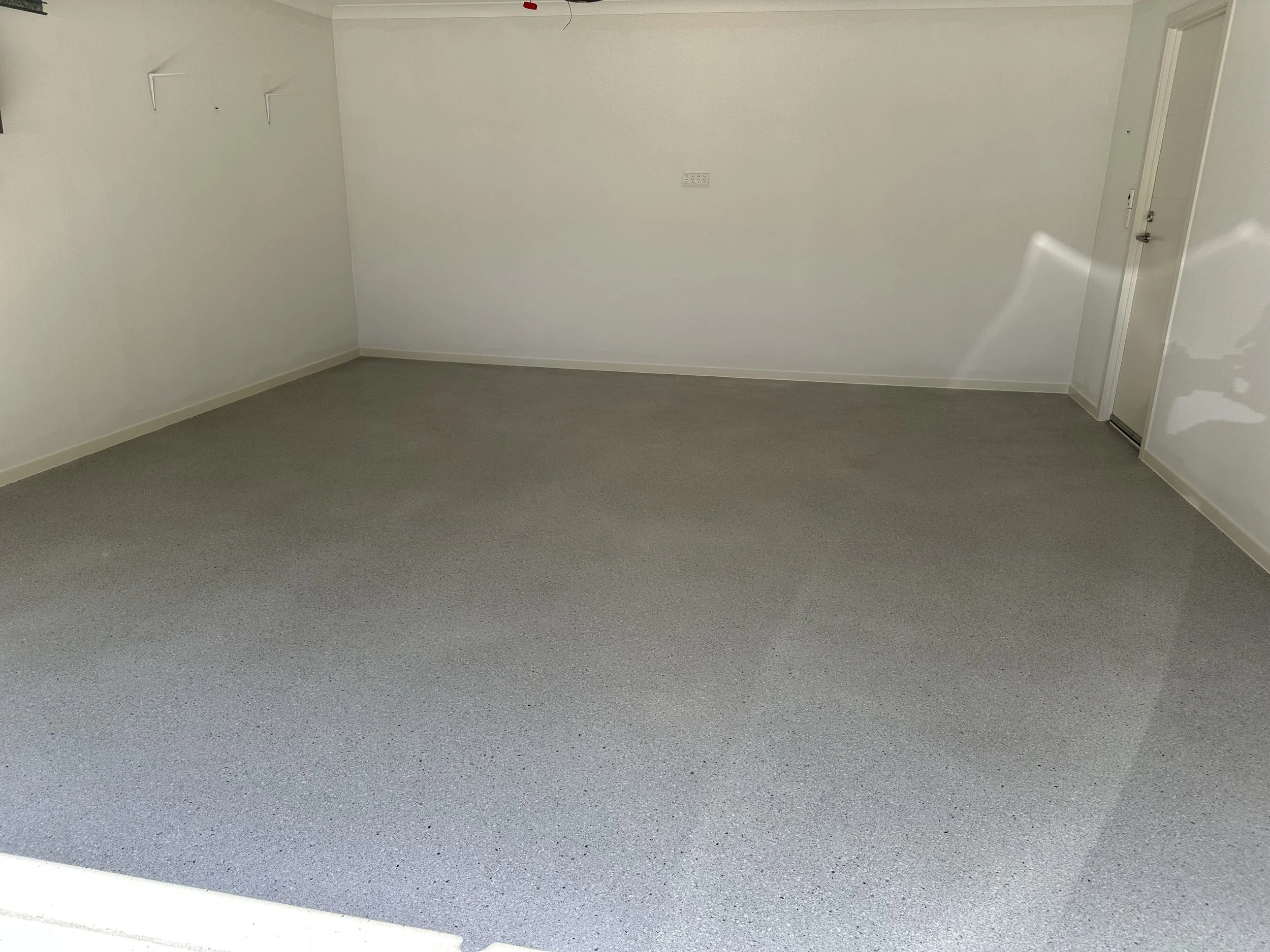 Empty room with white walls, gray carpet, and a white door.