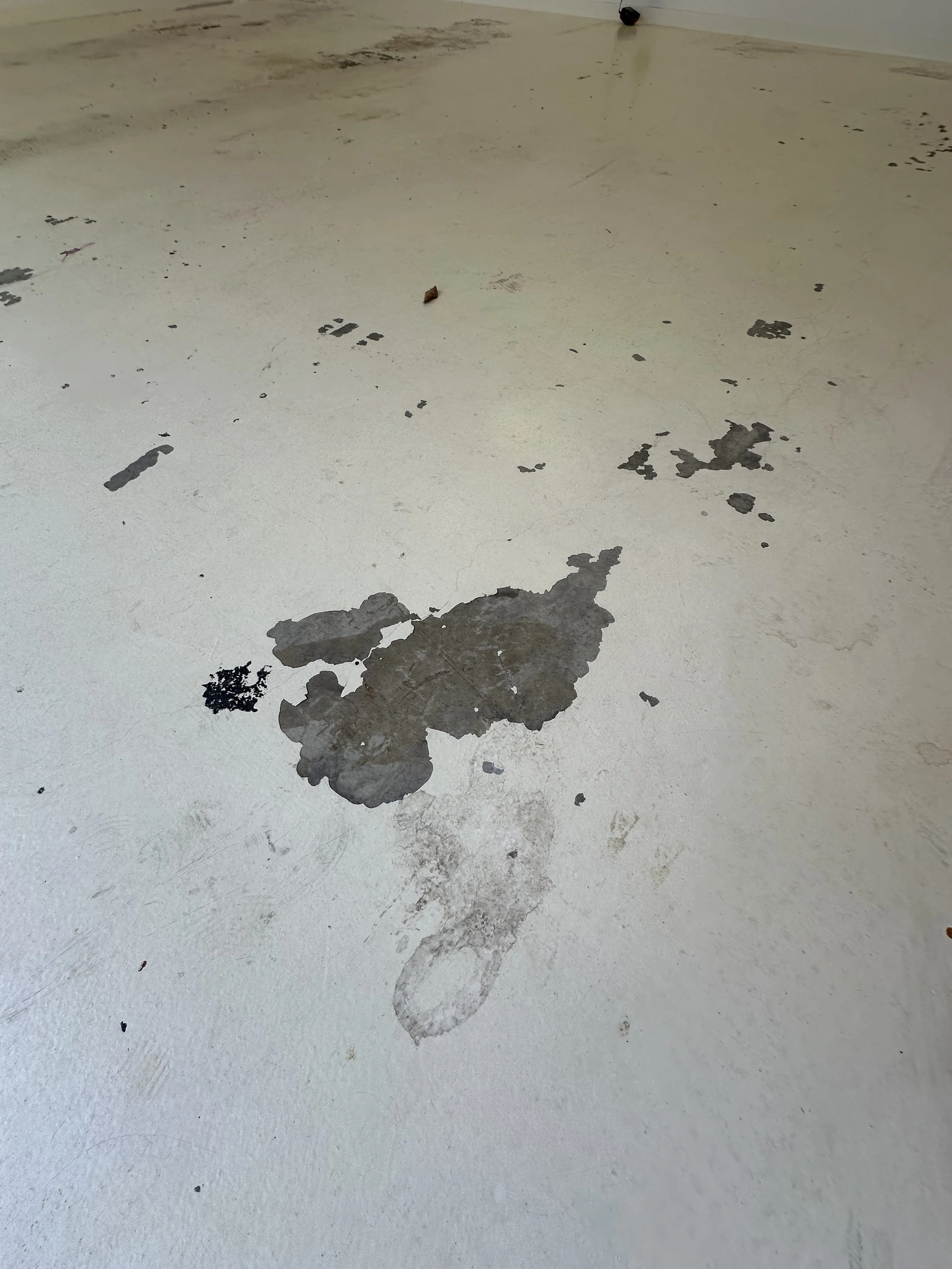 Concrete floor with peeling paint and a faint footprint at the bottom center