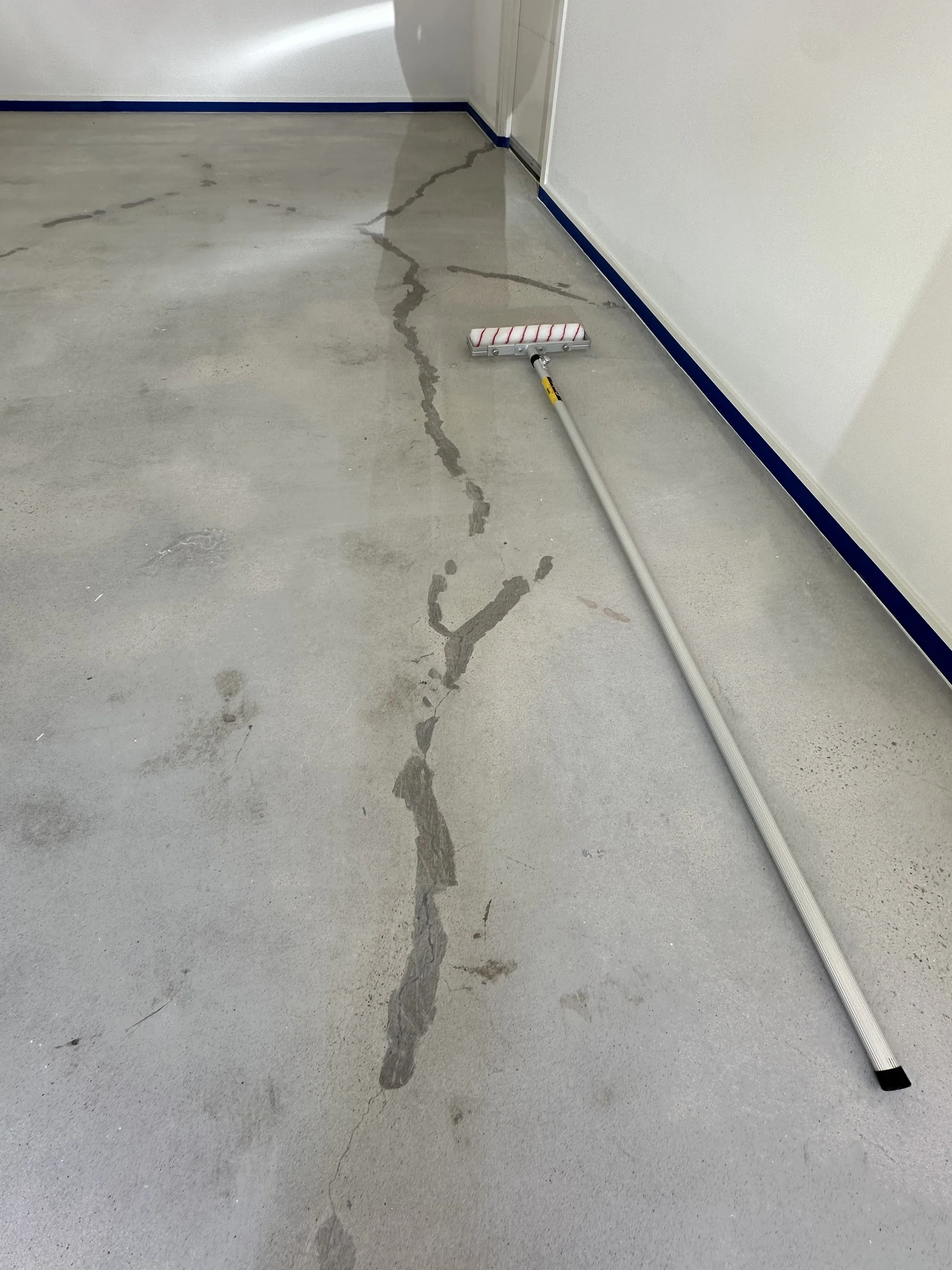 Concrete floor with visible cracks and a mop lying on the ground.
