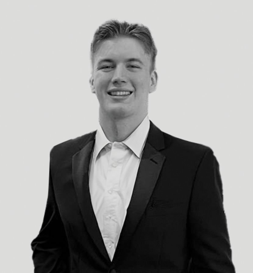 Young man in a tuxedo smiling, black and white photo.