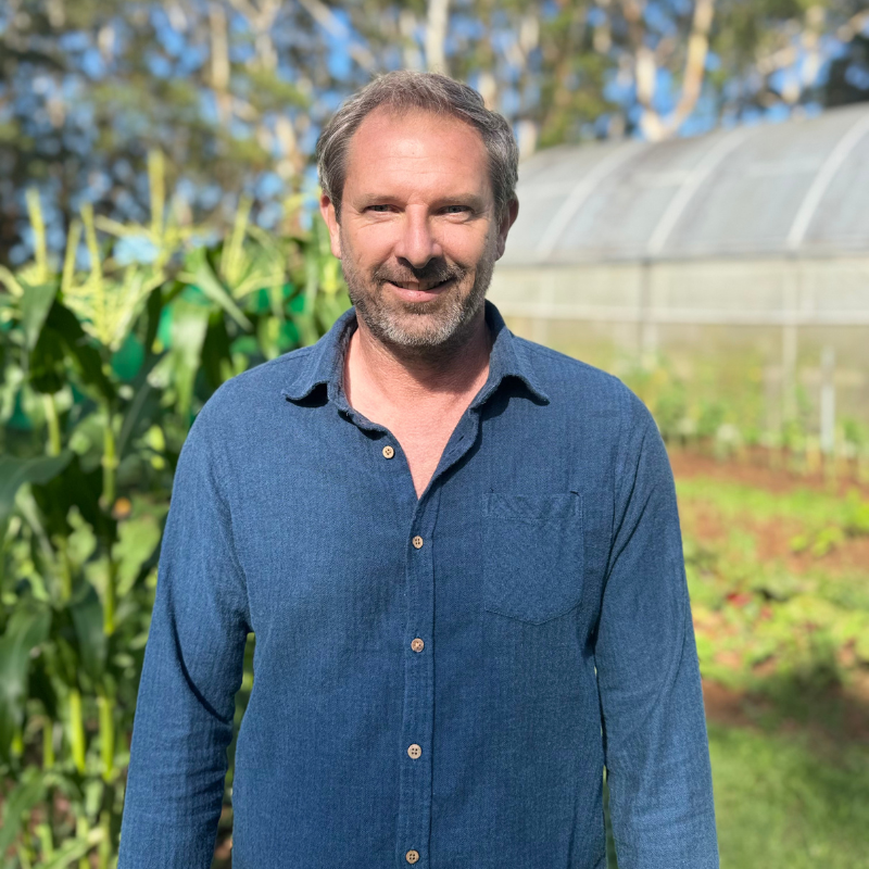 Alasdair Smithson standing in front of corn and polytunnel