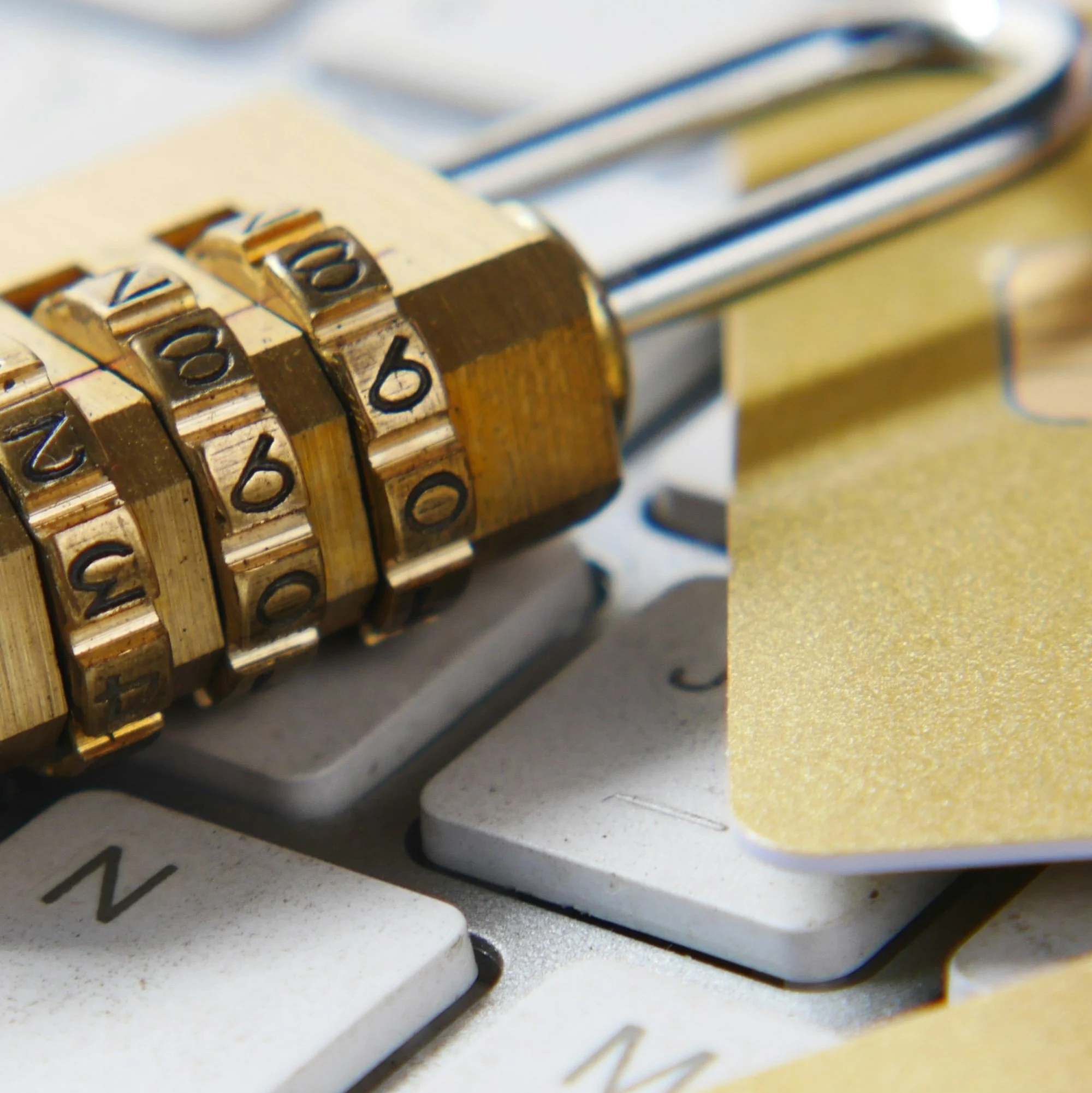 Close-up of a four-digit combination lock on a keyboard with a gold-colored sticky note.