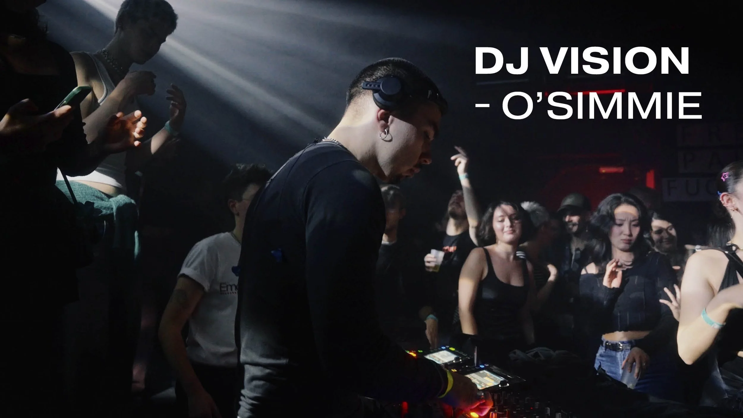 DJ Vision: DJ O'Simmie performing at a nightclub with a crowd dancing and enjoying music, dim lighting, and colorful flashing lights.