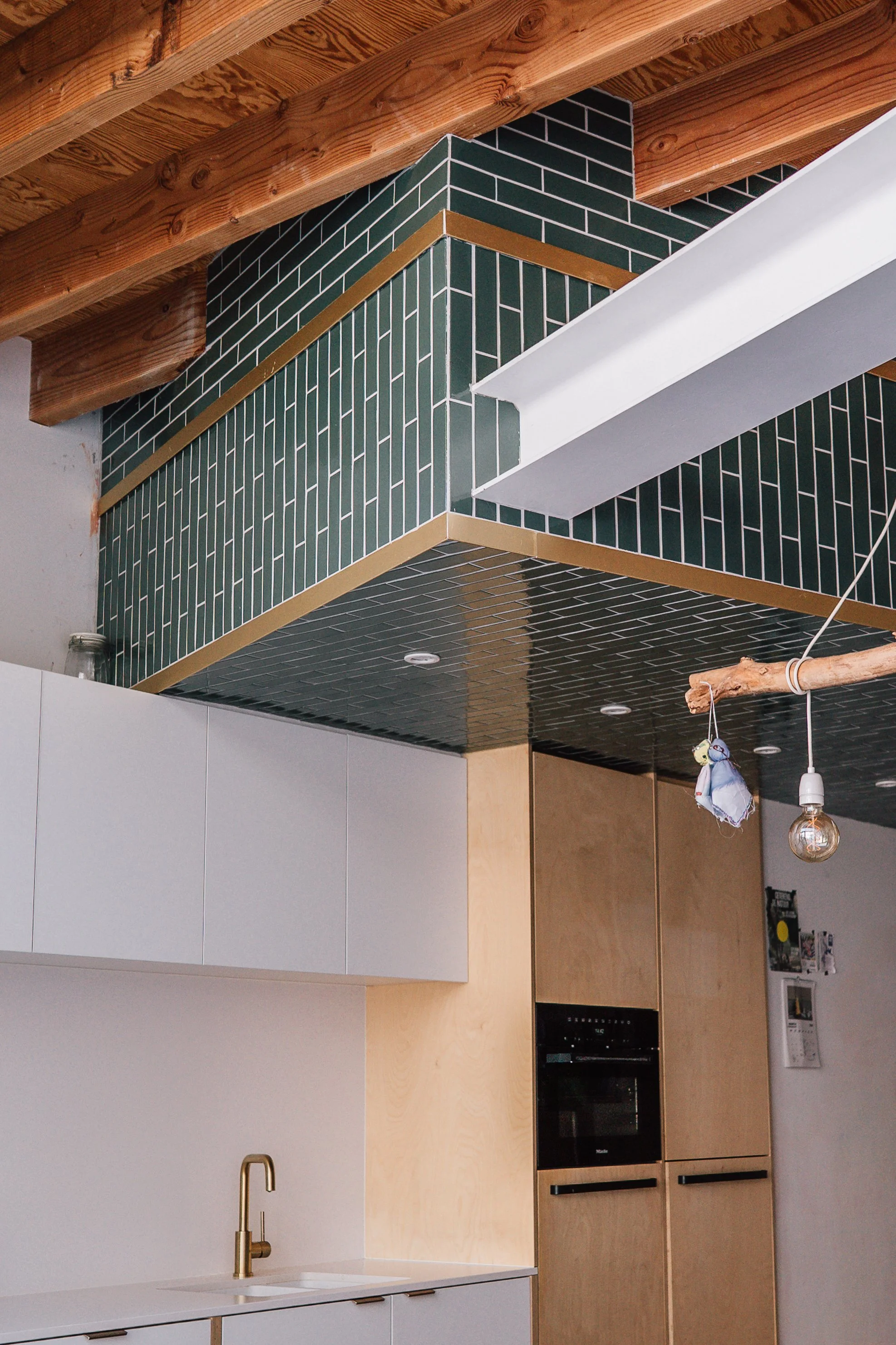 Stadswoning VHVW - Een fris groen volume met tegeltjes in een houtskelet extensie die een gezellige keuken bevat met een combinatie van houten en witte kastelementen. Een groot daklicht zorgt voor de nodige lichtinval.