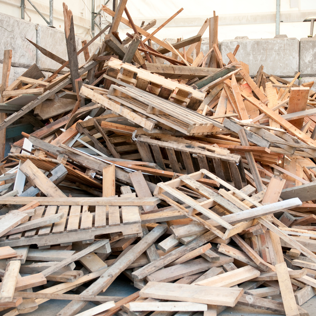 Pile of discarded wooden pallets and scrap wood in a construction or storage area.