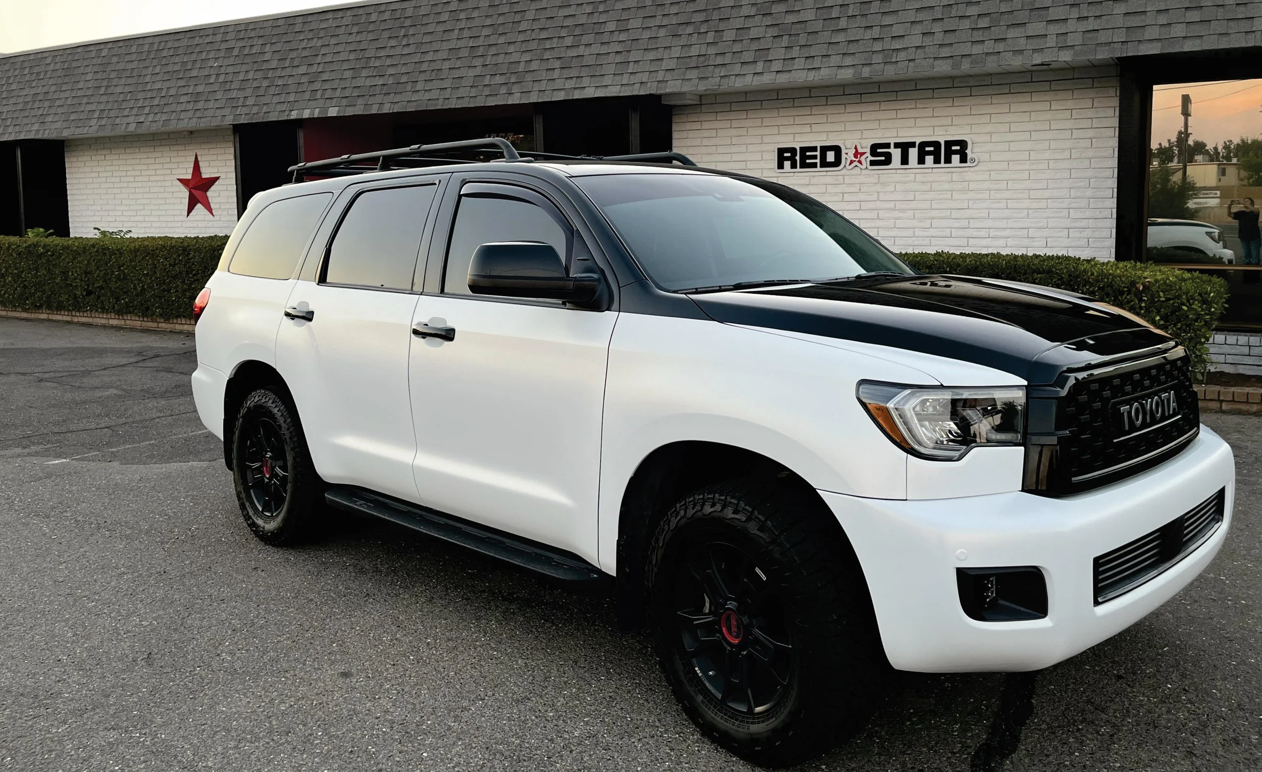 White and black Toyota SUV parked in front of a building with a Red Star sign.