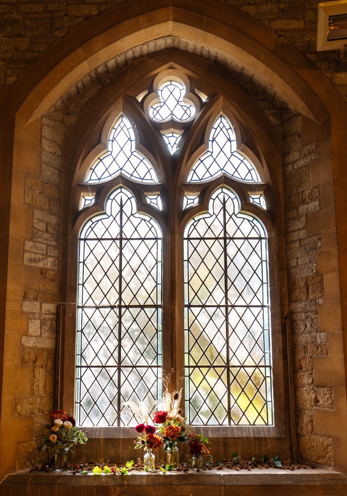 Decorated window with stained glass, featuring floral arrangements on the windowsill.