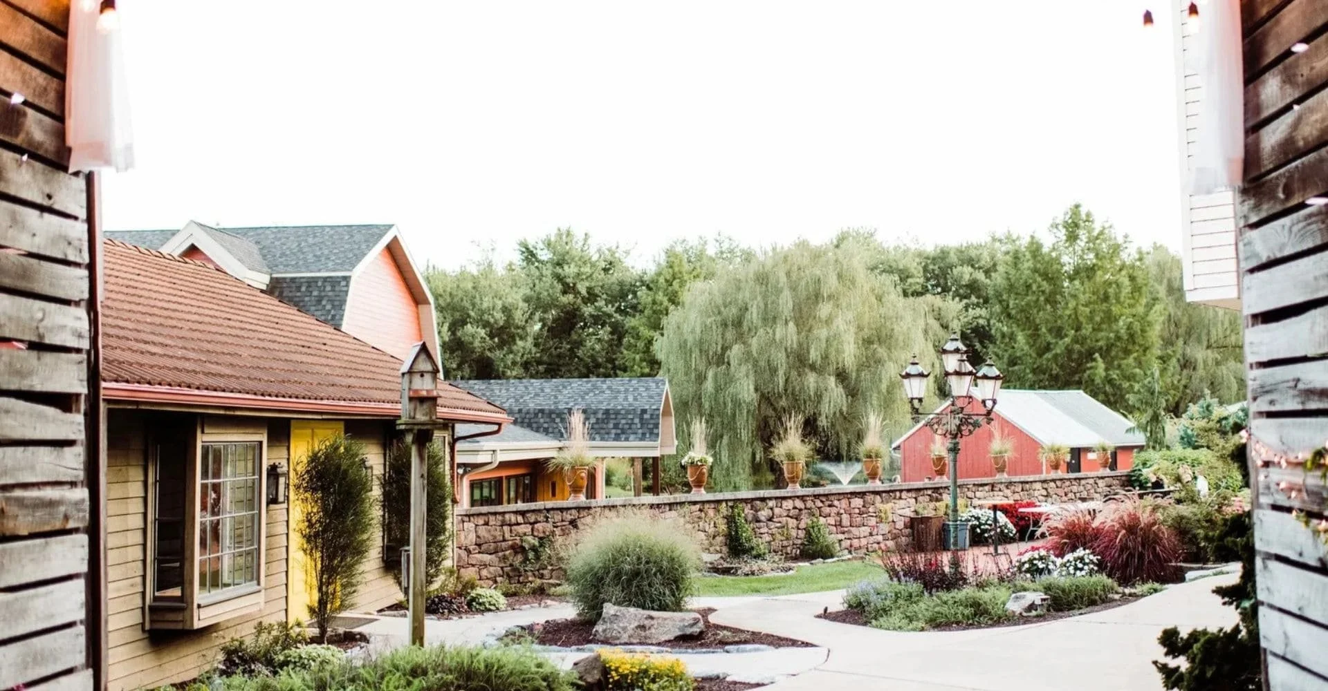 A small courtyard surrounded by historic building and enclosed by a wooden fence, featuring greenery and a tranquil atmosphere