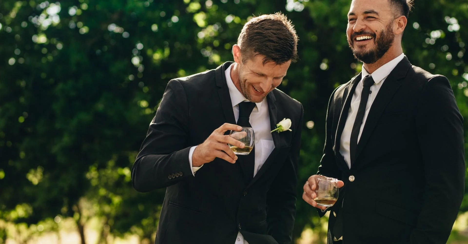 Two men in formal suits raise their wine glasses, enjoying a toast in a sophisticated setting.