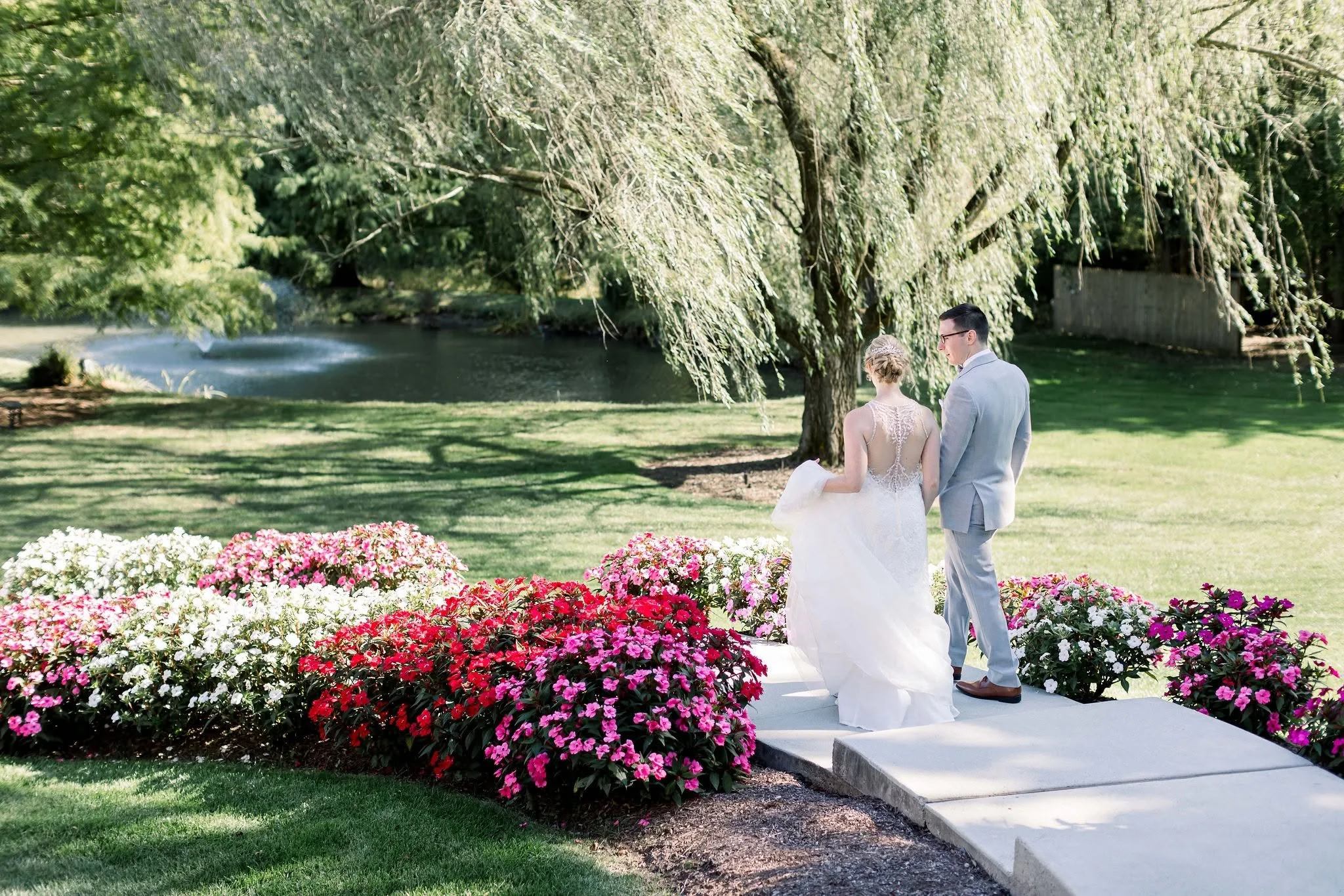 A wedding photographer captures a couple's joyful moment outdoors in Pennsylvania, surrounded by lush greenery and soft sunlight.