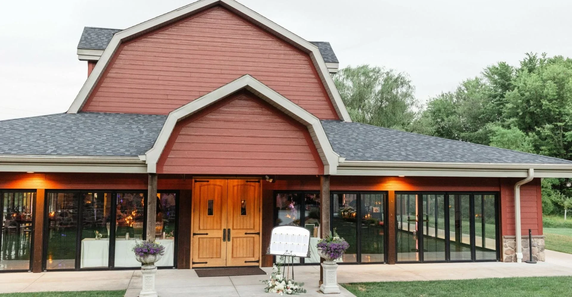 A red barn featuring a glass door and a sign reading "wedding," set against a clear blue sky.