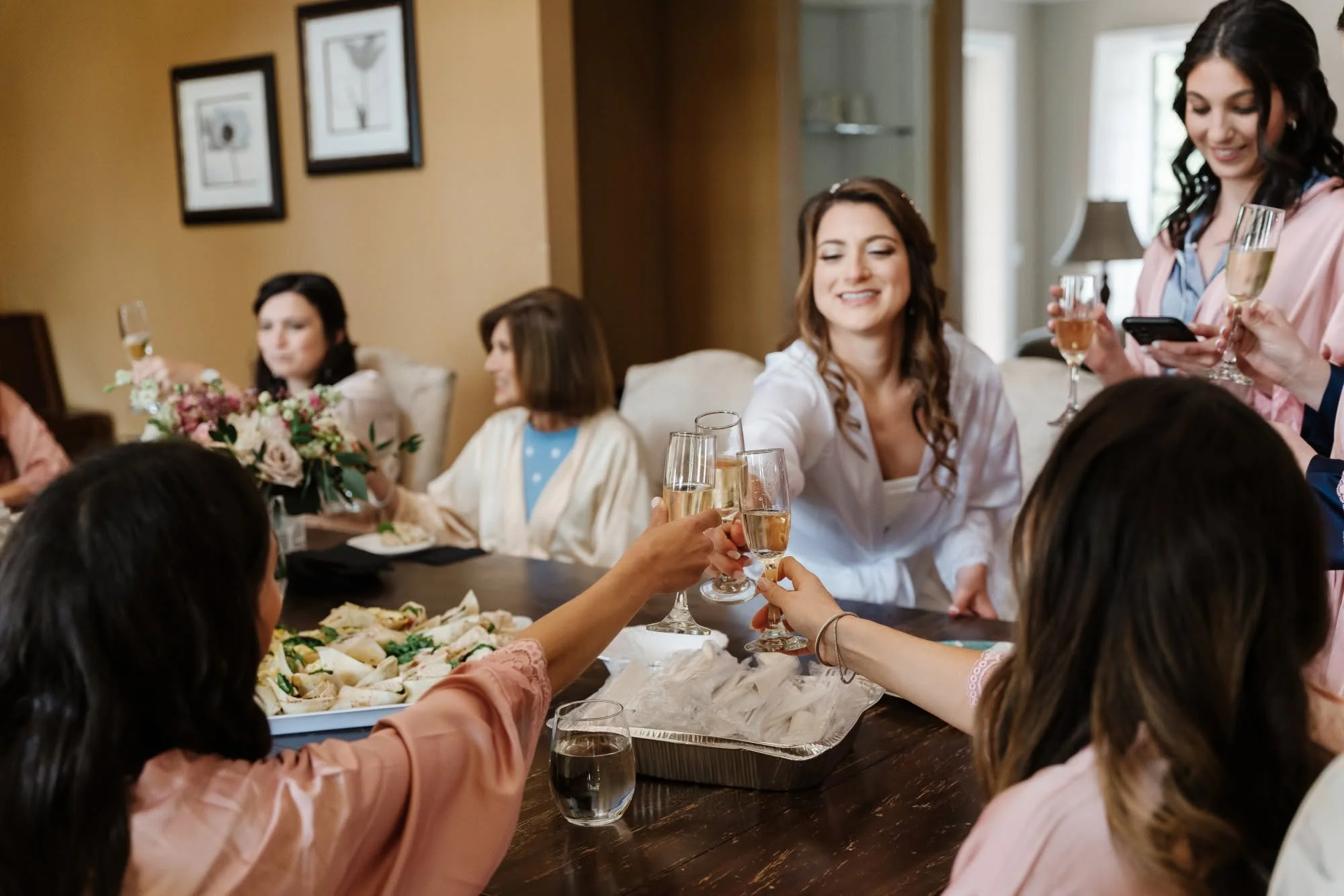 Bridesmaids raise their glasses in a joyful toast during a wedding reception, celebrating love and friendship.