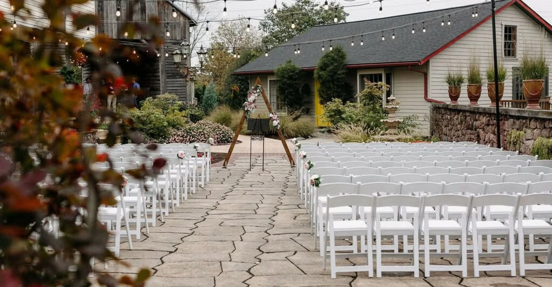 Outdoor wedding ceremony at a picturesque winery, featuring elegant decorations and guests seated under a clear sky.