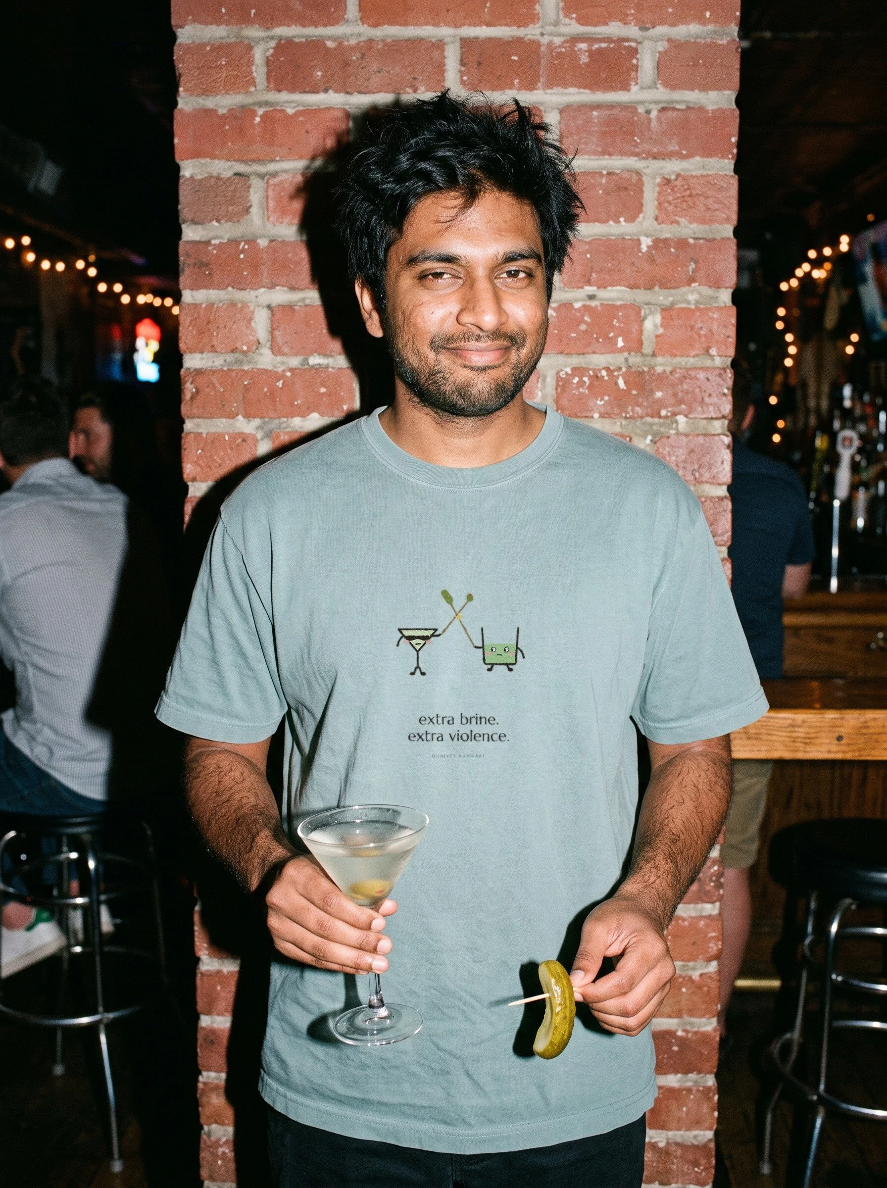 Man at a dive bar in a Bay The Brine Duel tee