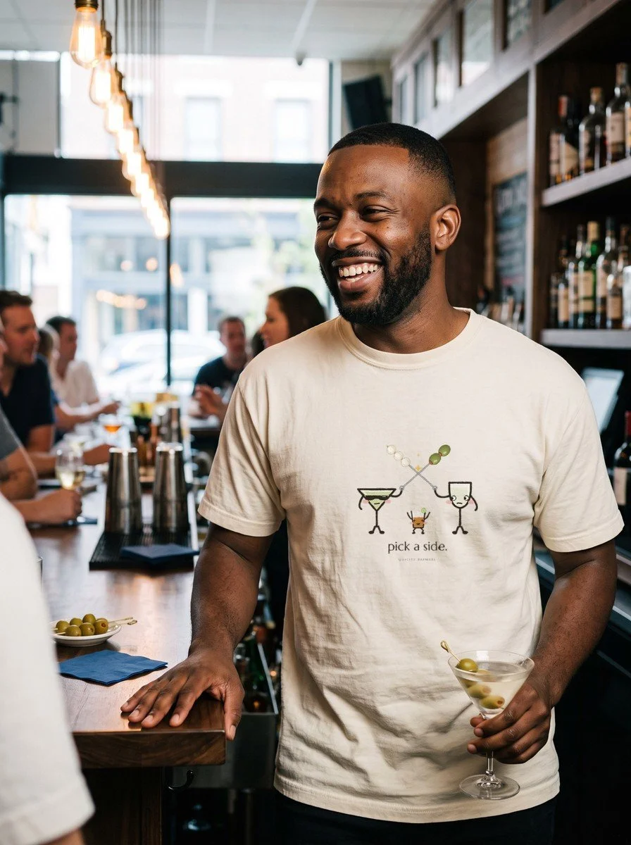 Man laughing at a cocktail bar in an Ivory The Garnish War tee