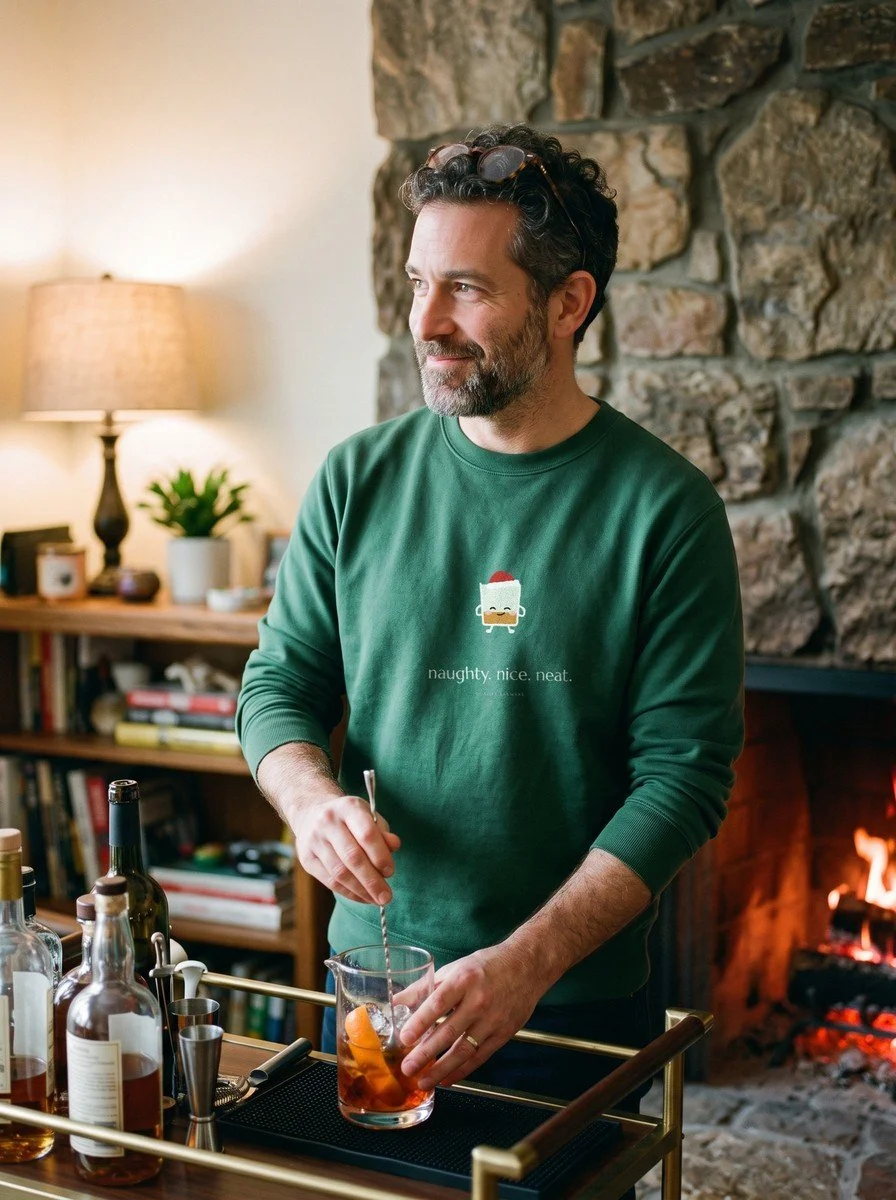 Man by a fireplace in a Forest Green The Neat List crewneck
