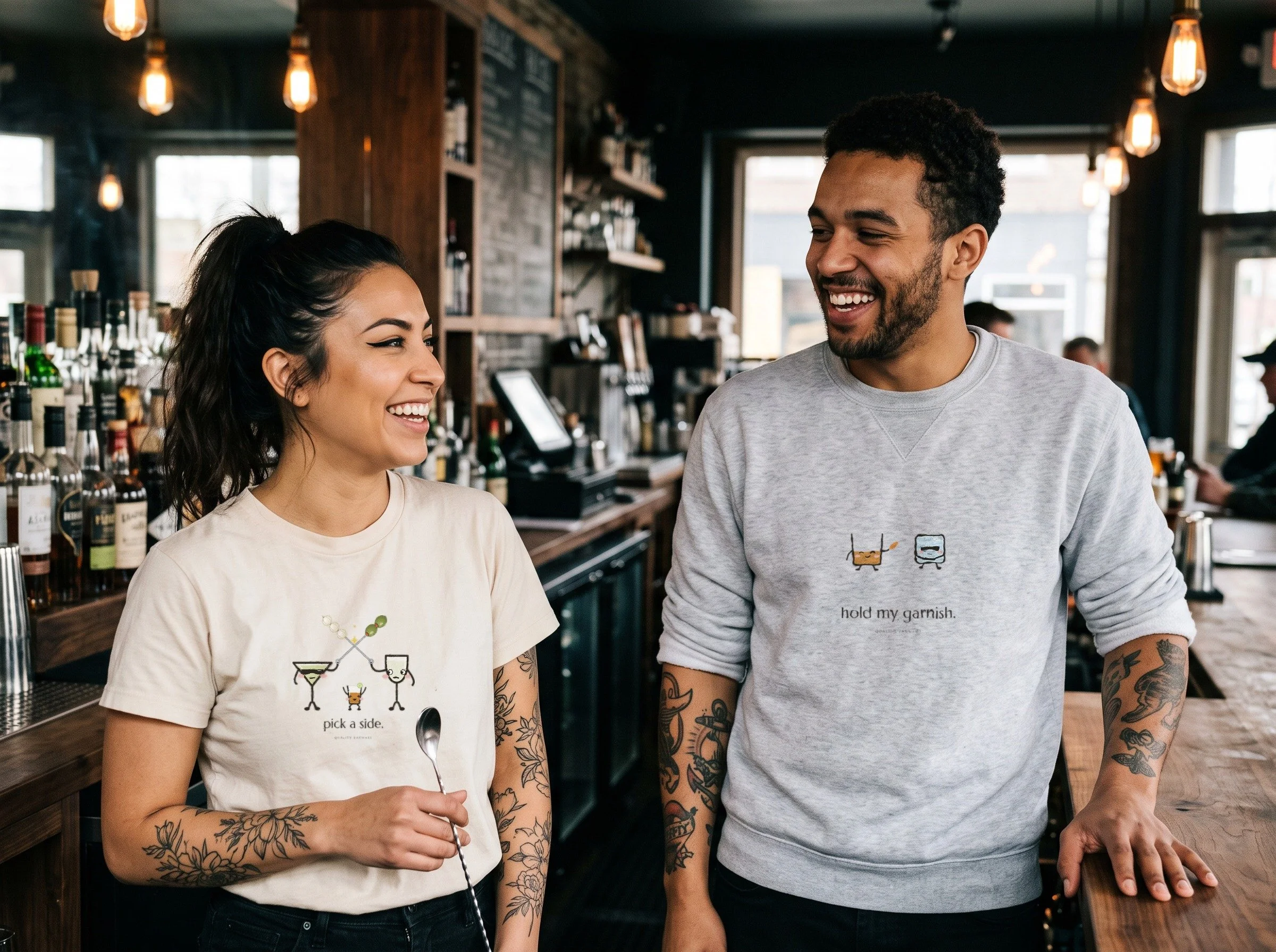 Two bartenders behind a bar in Lil Pours The Garnish War and The Bodyguard shirts