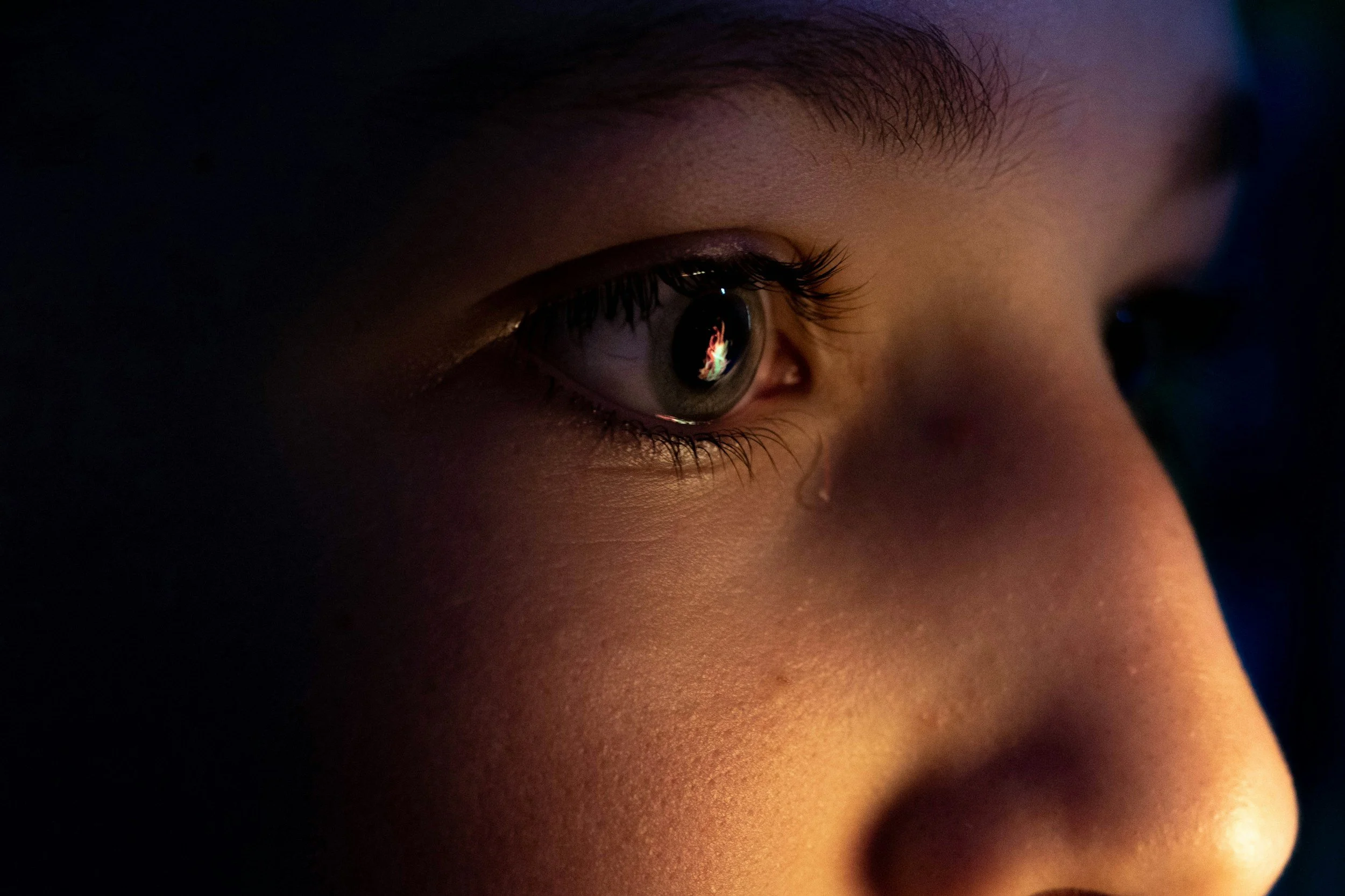 Close-up of a person’s eye with a tear visible on their cheek