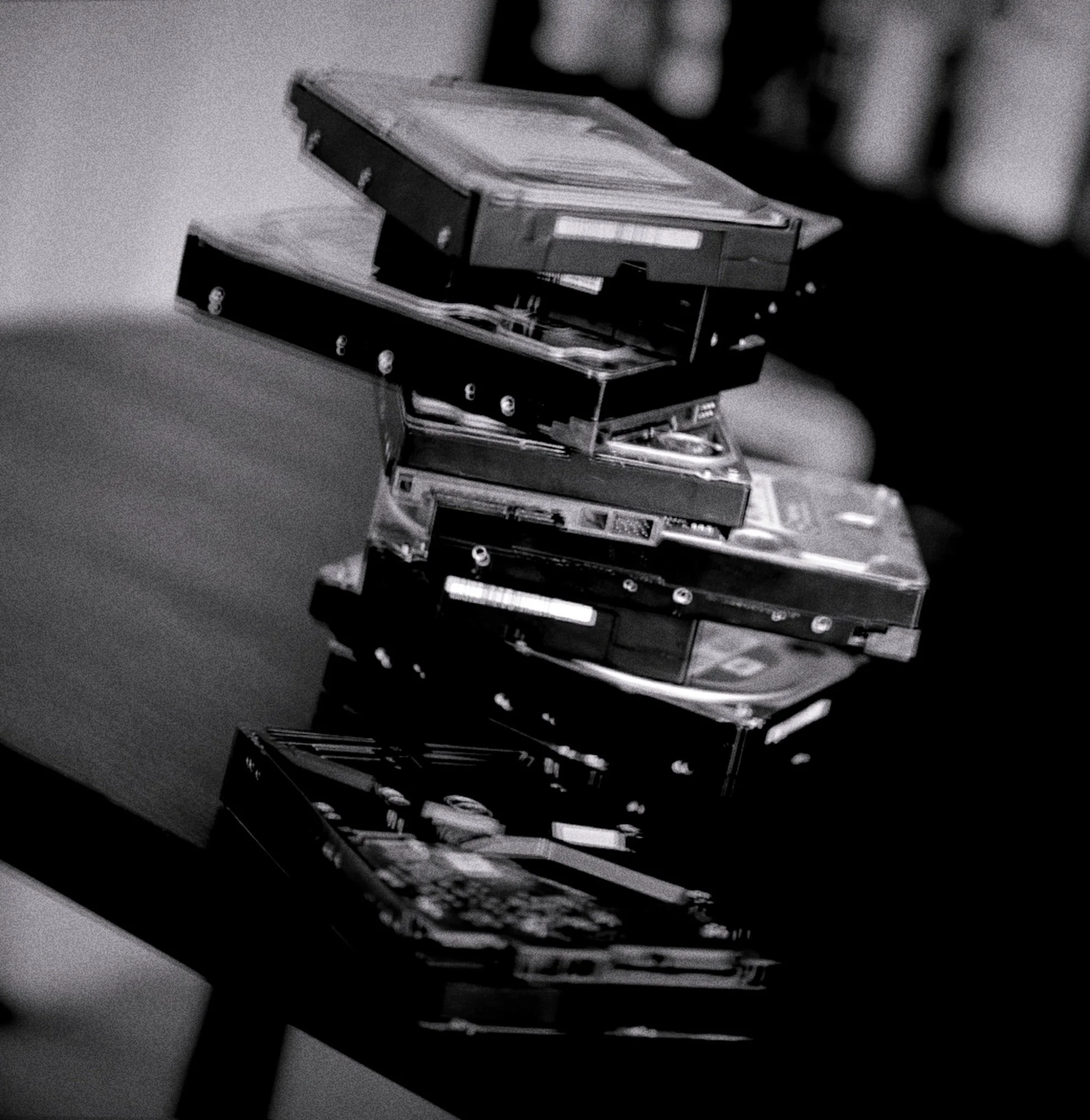 A teetering stack of hard disk drives with heavy blur and film grain