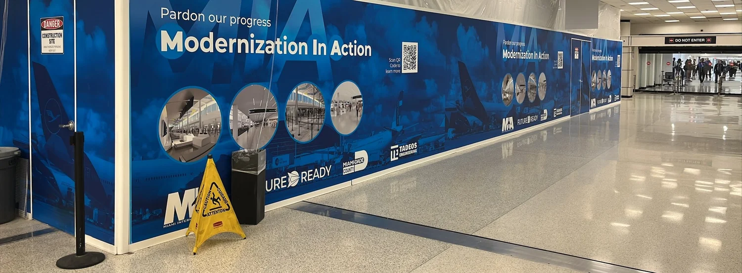 Finished 16 ft SwiftWall Pro barricade in the public concourse at Miami International Airport Terminal K, beside Baggage Claim signage