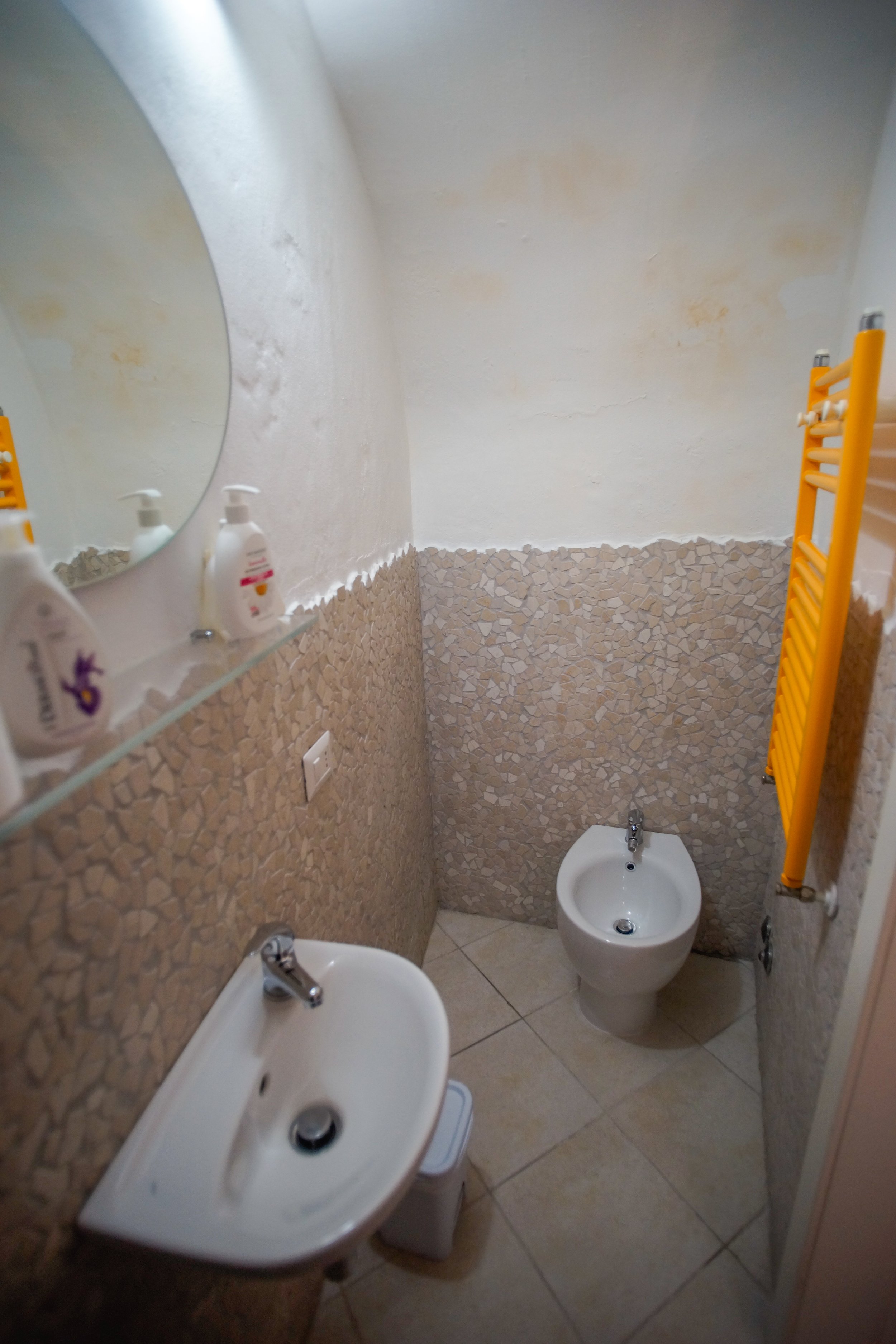 Bagno piccolo con lavabo, bidet, scaldasalviette giallo e specchio