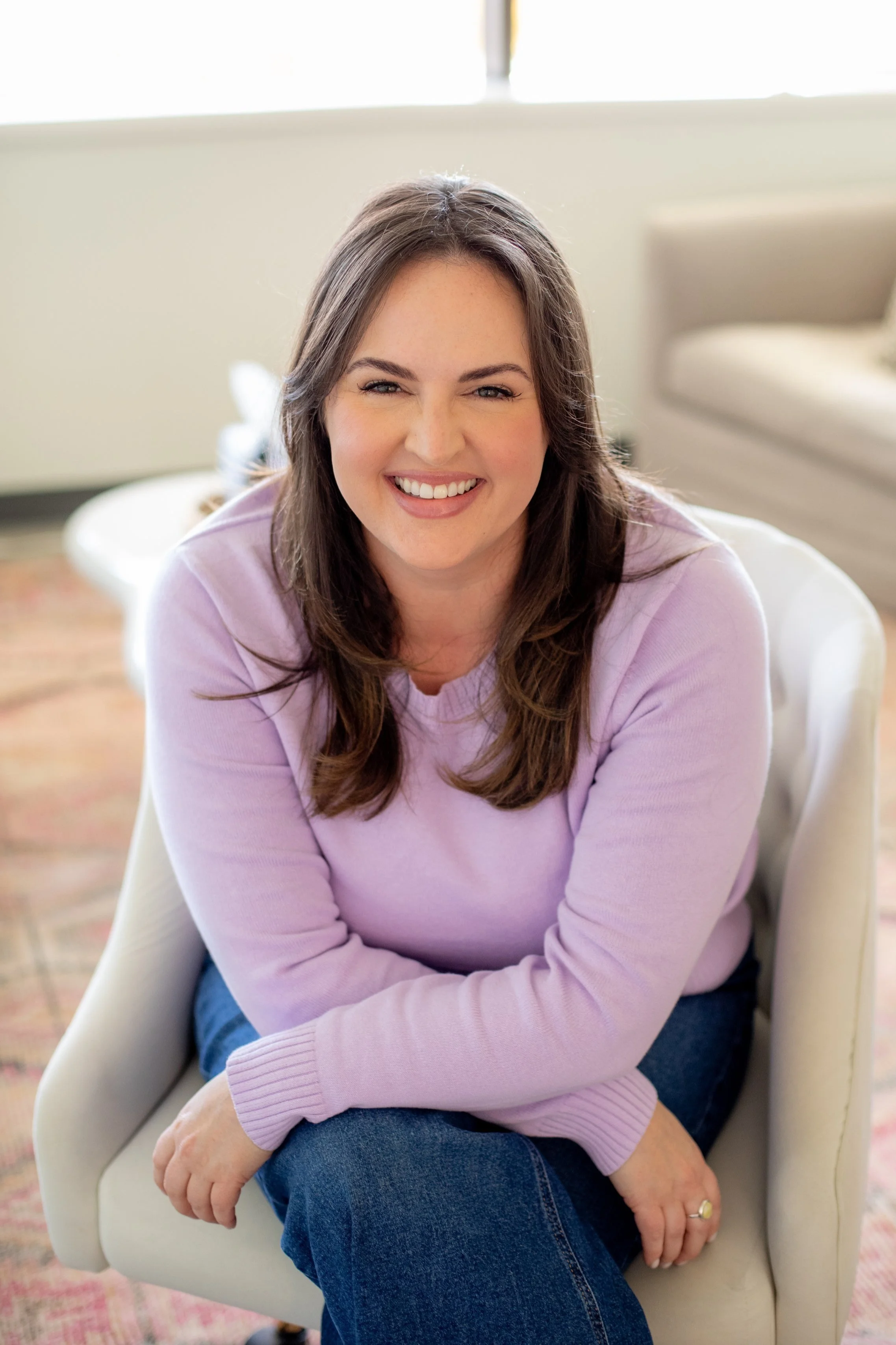 EMDR therapist and somatic therapist in Kansas City sitting in a chair wearing a purple swater