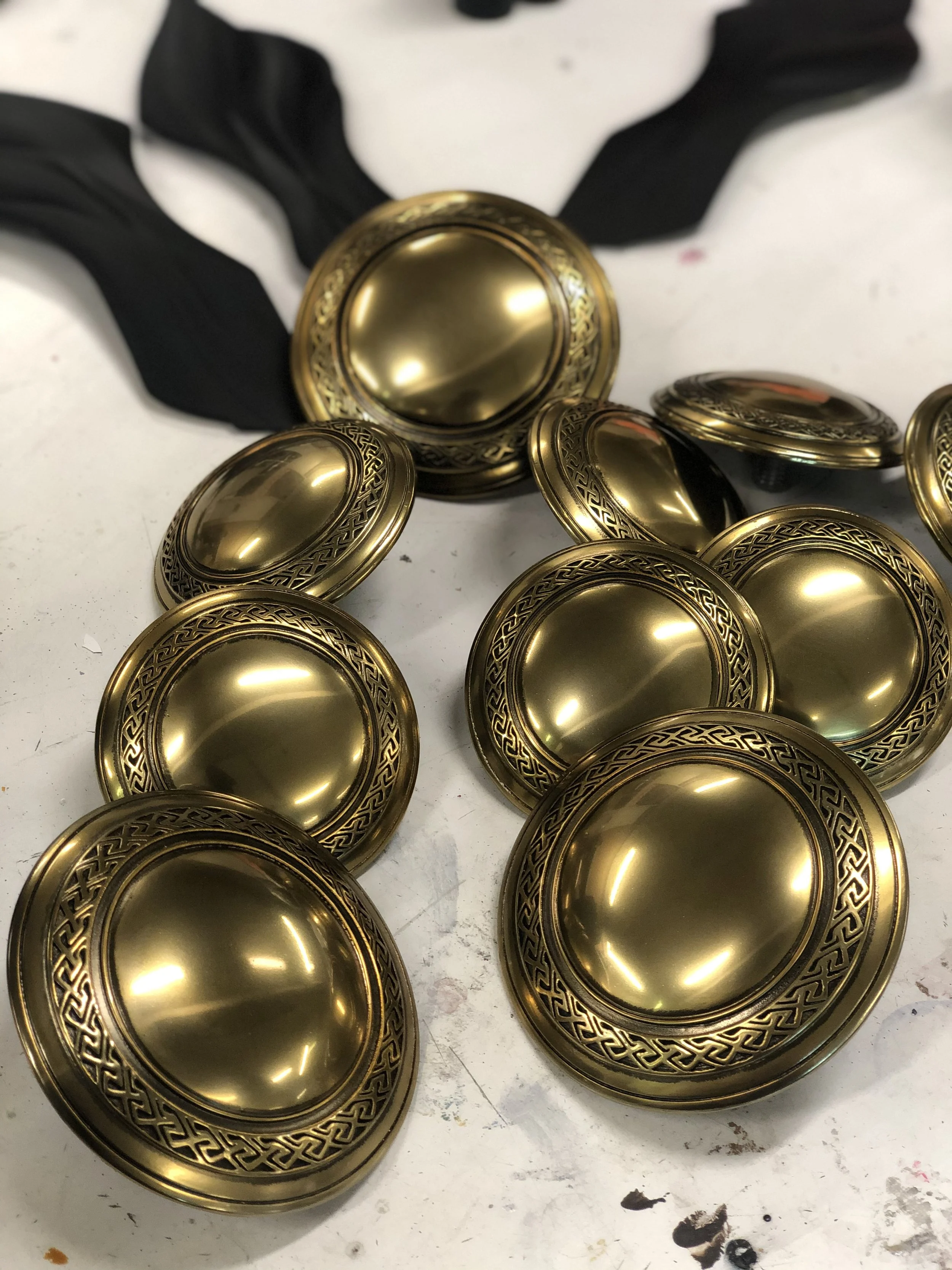 Several gold-colored metallic medals with black ribbons on a white surface.