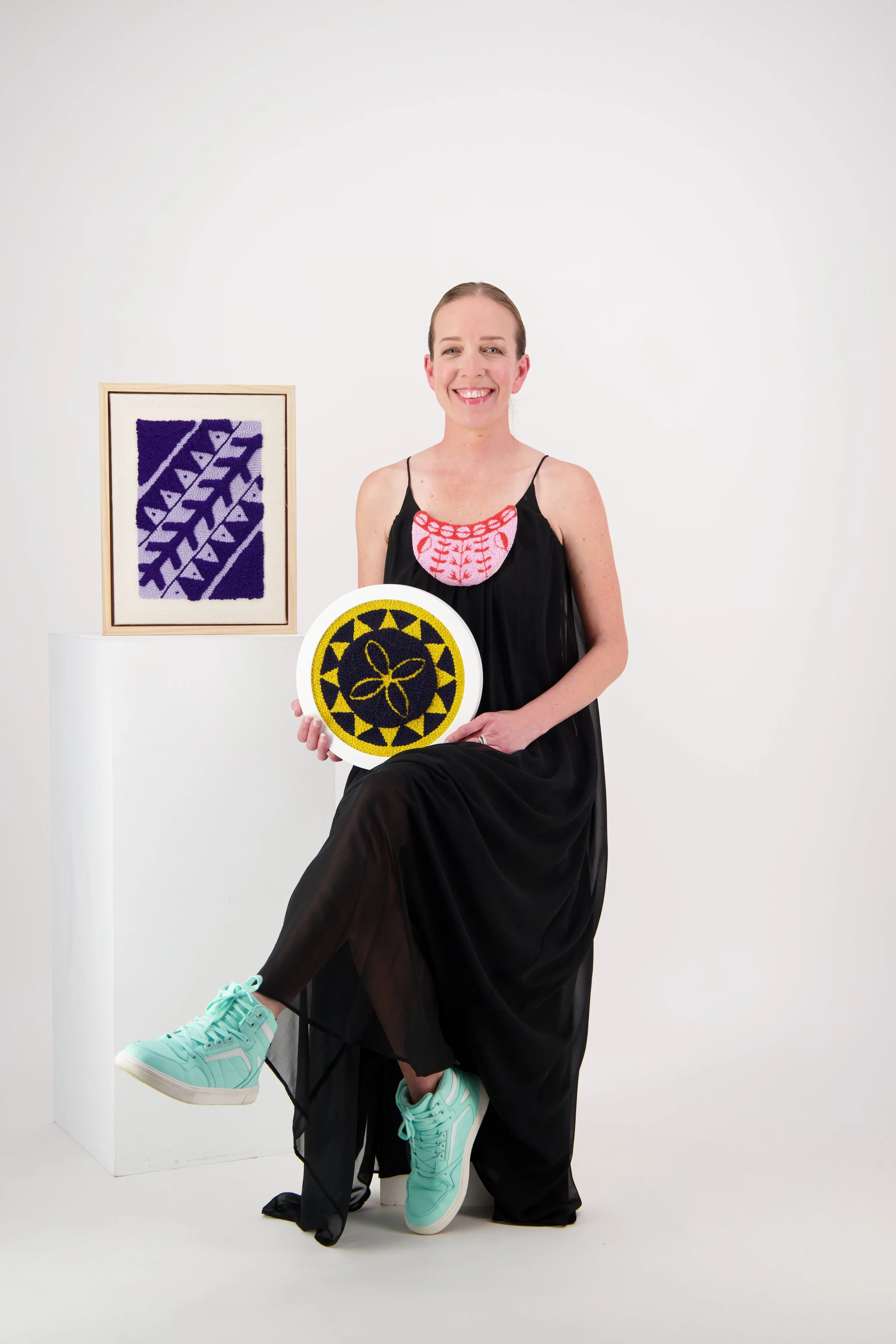 Artist Natalie Holland surrounded by colourful wool and textile artworks.