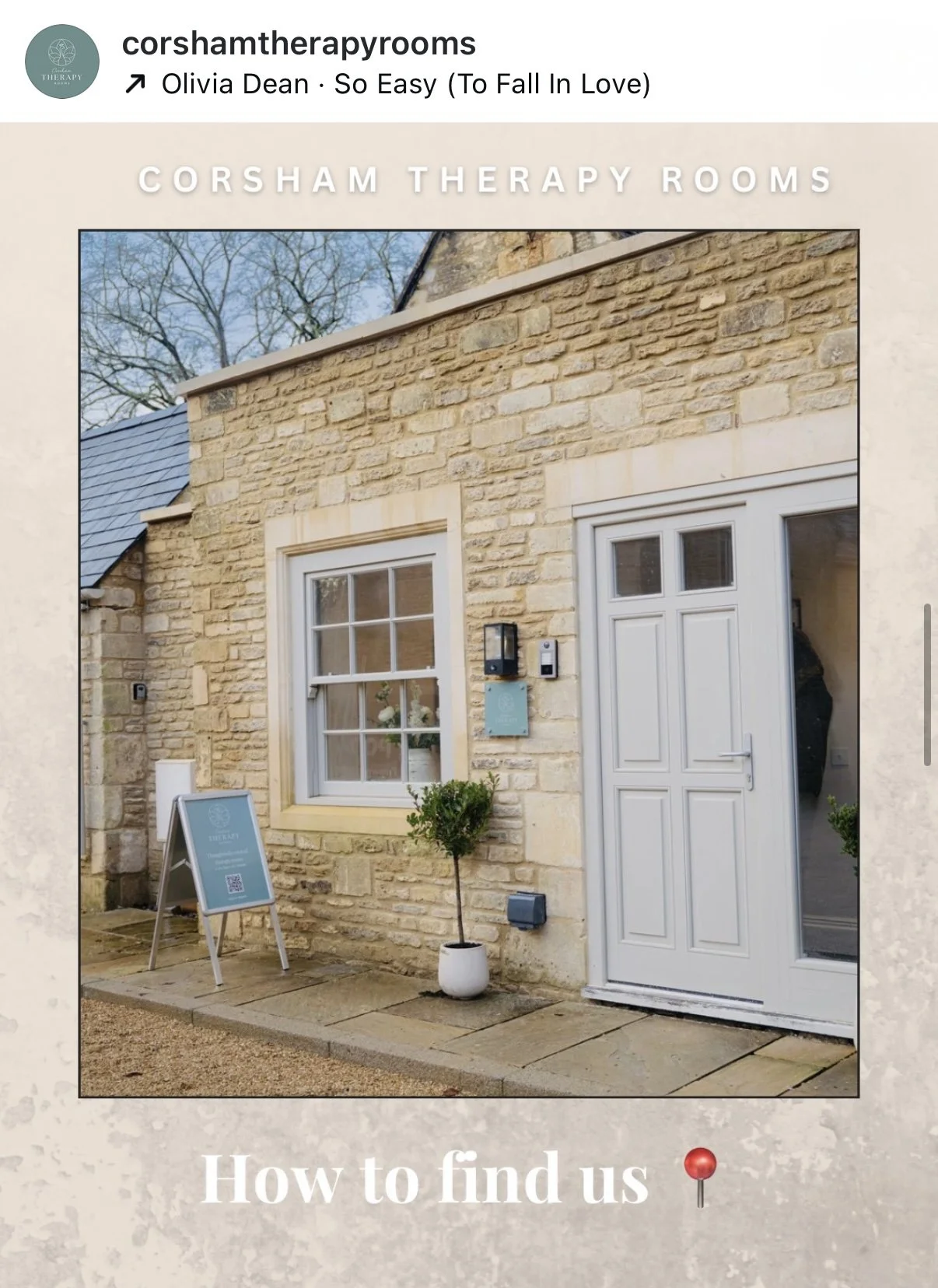 A beige stone building with a white door and window. There is a small potted plant, a signboard, and an advertisement board outside. The building is part of a therapy room.