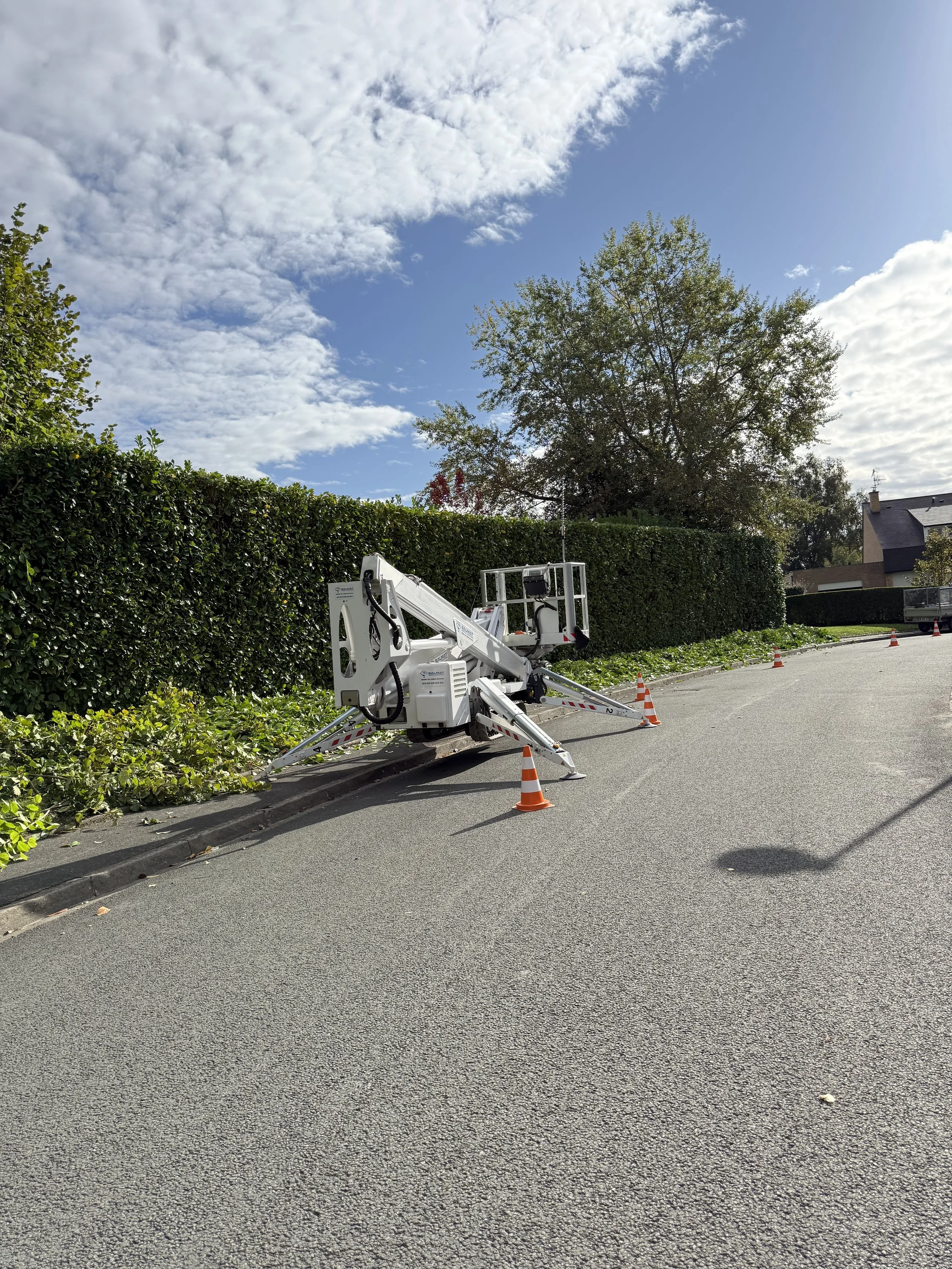 Un carrefour de voirie avec une plateforme élévatrice et des cônes de signalisation orange et blanc