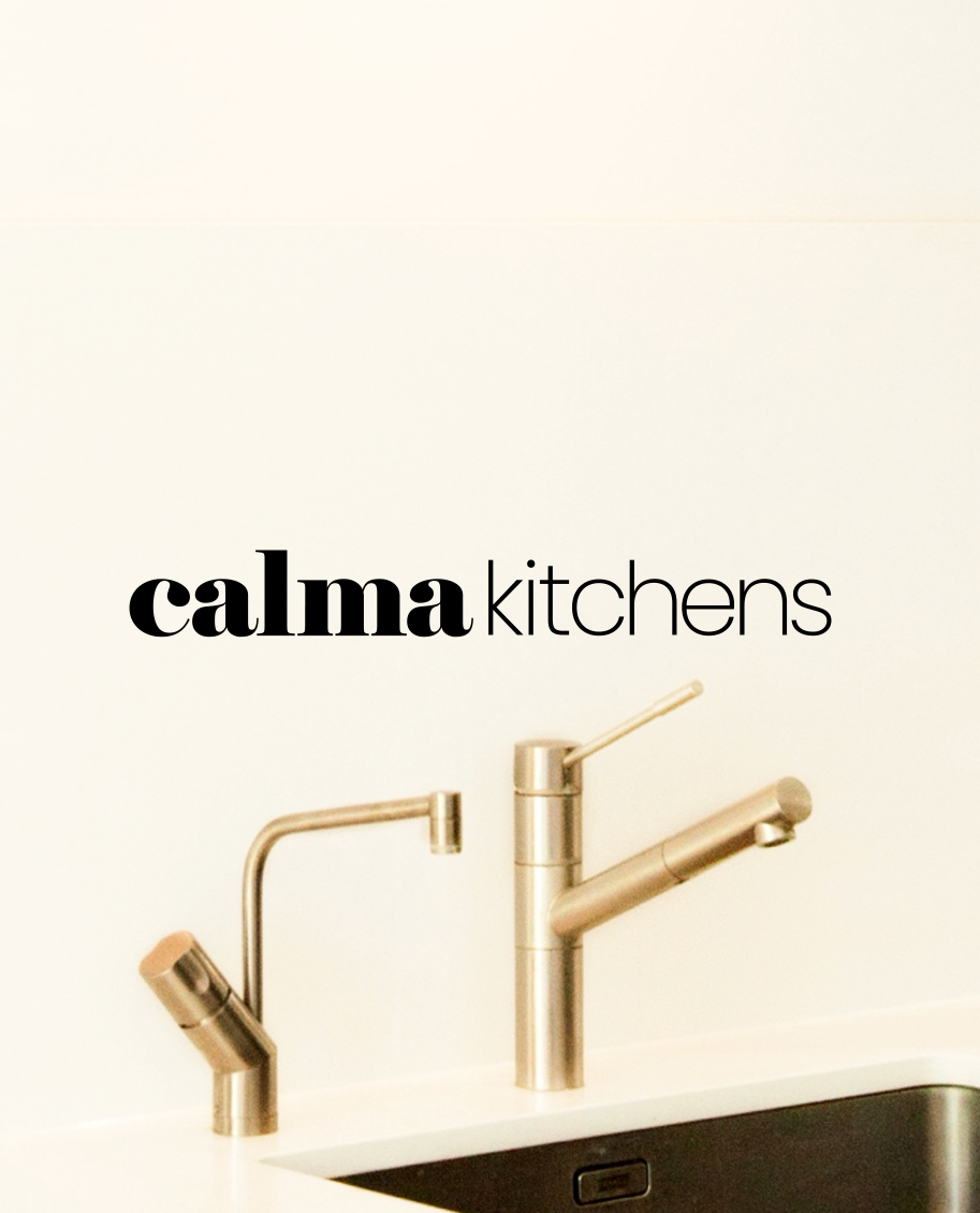 Showroom kitchen faucets with the store name 'Calma Kitchens' on the wall.