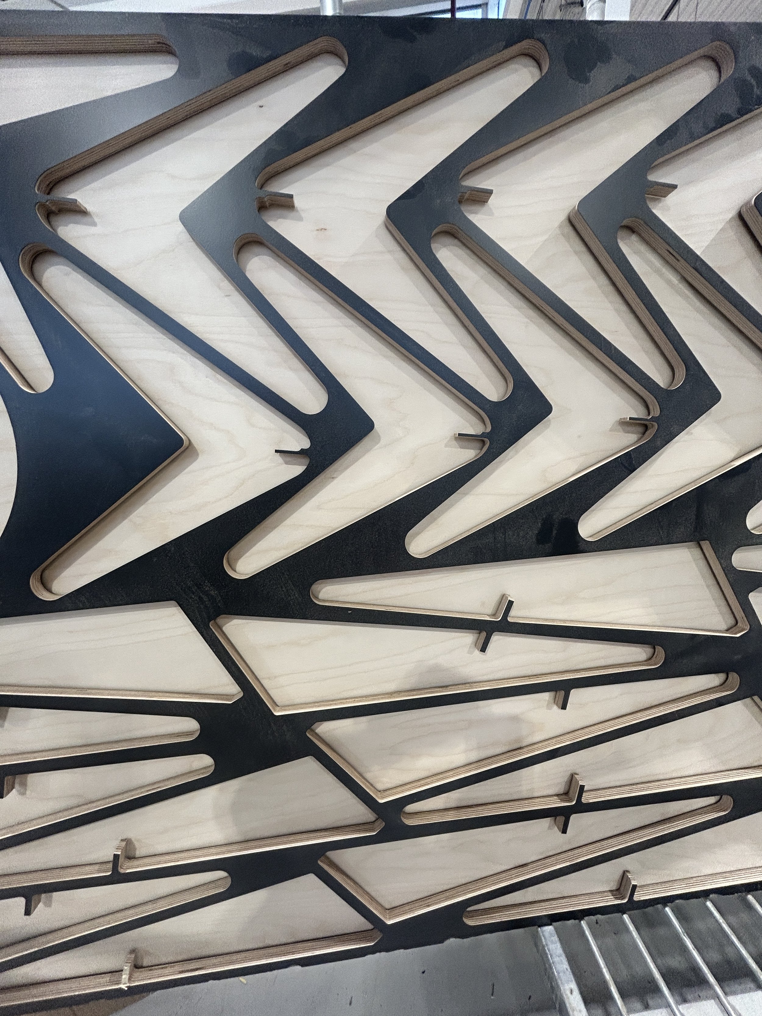 Stacked black and light wood-colored metal or plastic frames with elongated, angular cutouts.