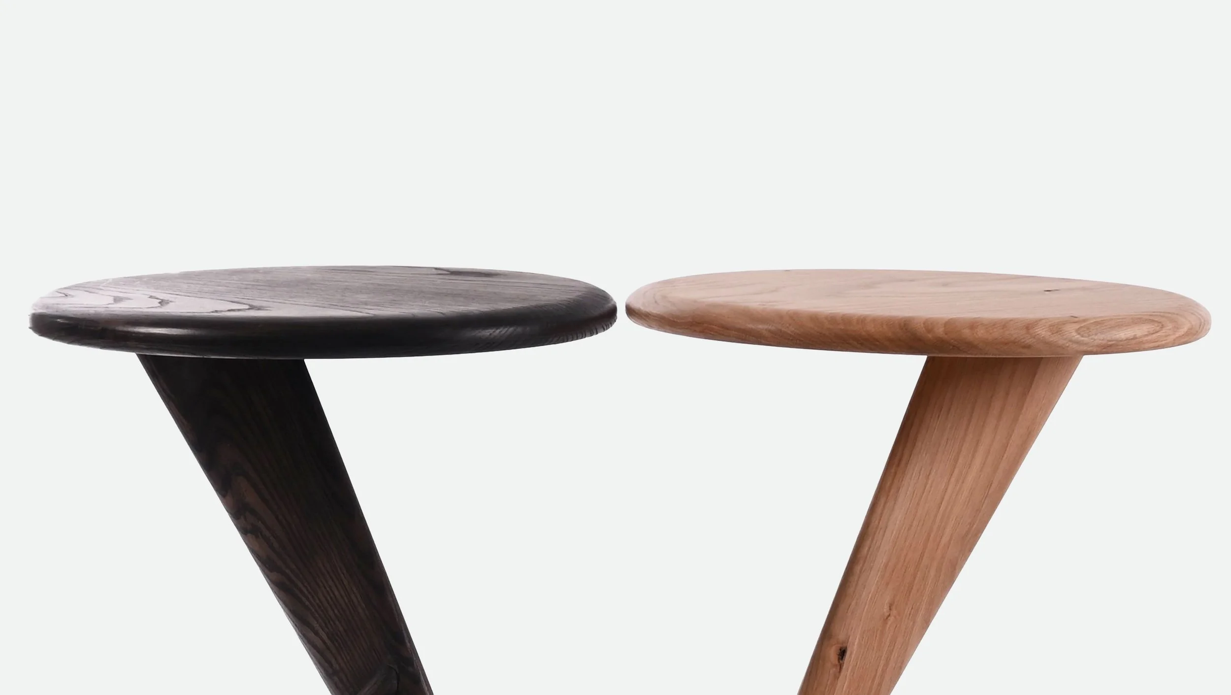 Two wooden stools, one dark stained and one natural light, placed side by side against a plain white background.