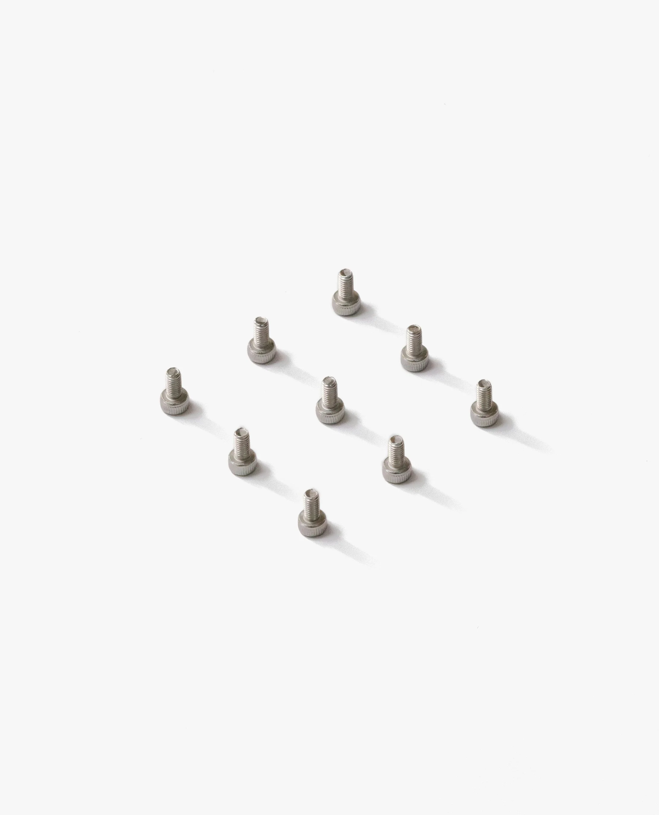 Multiple small metal screws arranged in a grid pattern on a white background