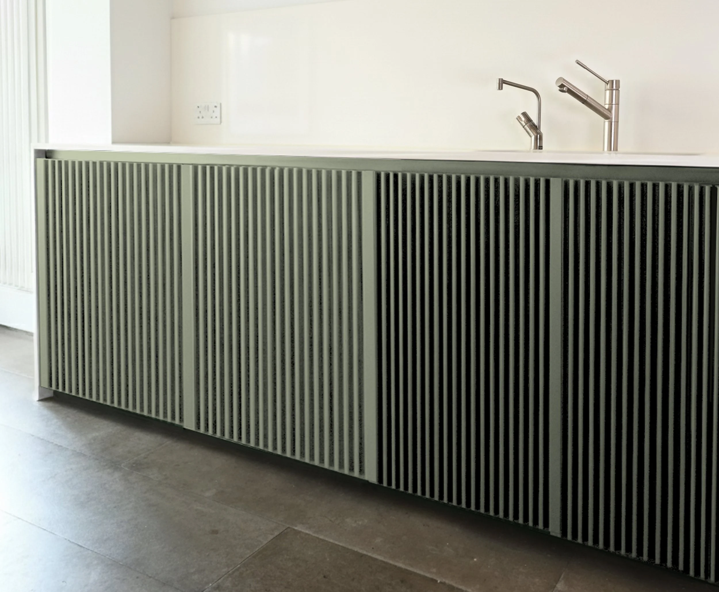 Modern kitchen island with vertically slatted black and white cabinets, a white countertop, and two stainless steel kitchen faucets on a clean, minimalistic kitchen.