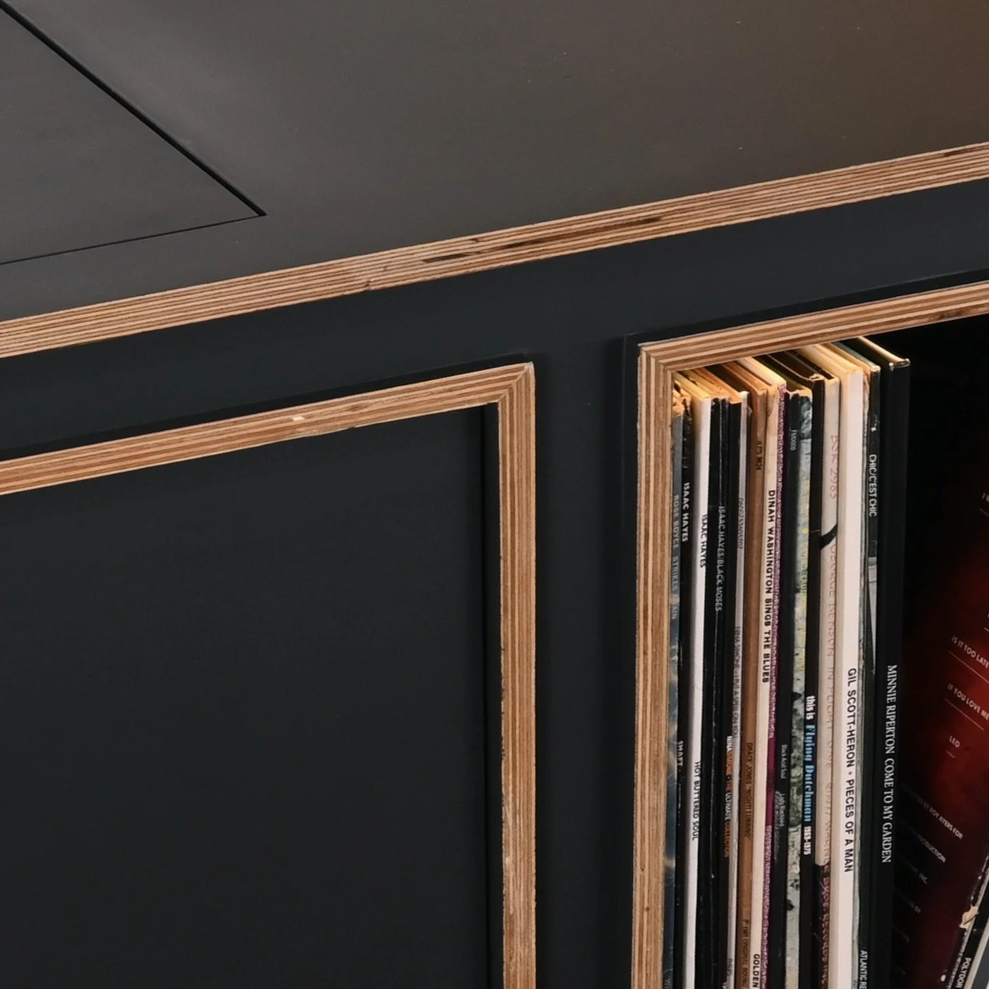 Close-up of a black bookshelf with wooden trim, filled with vinyl records.