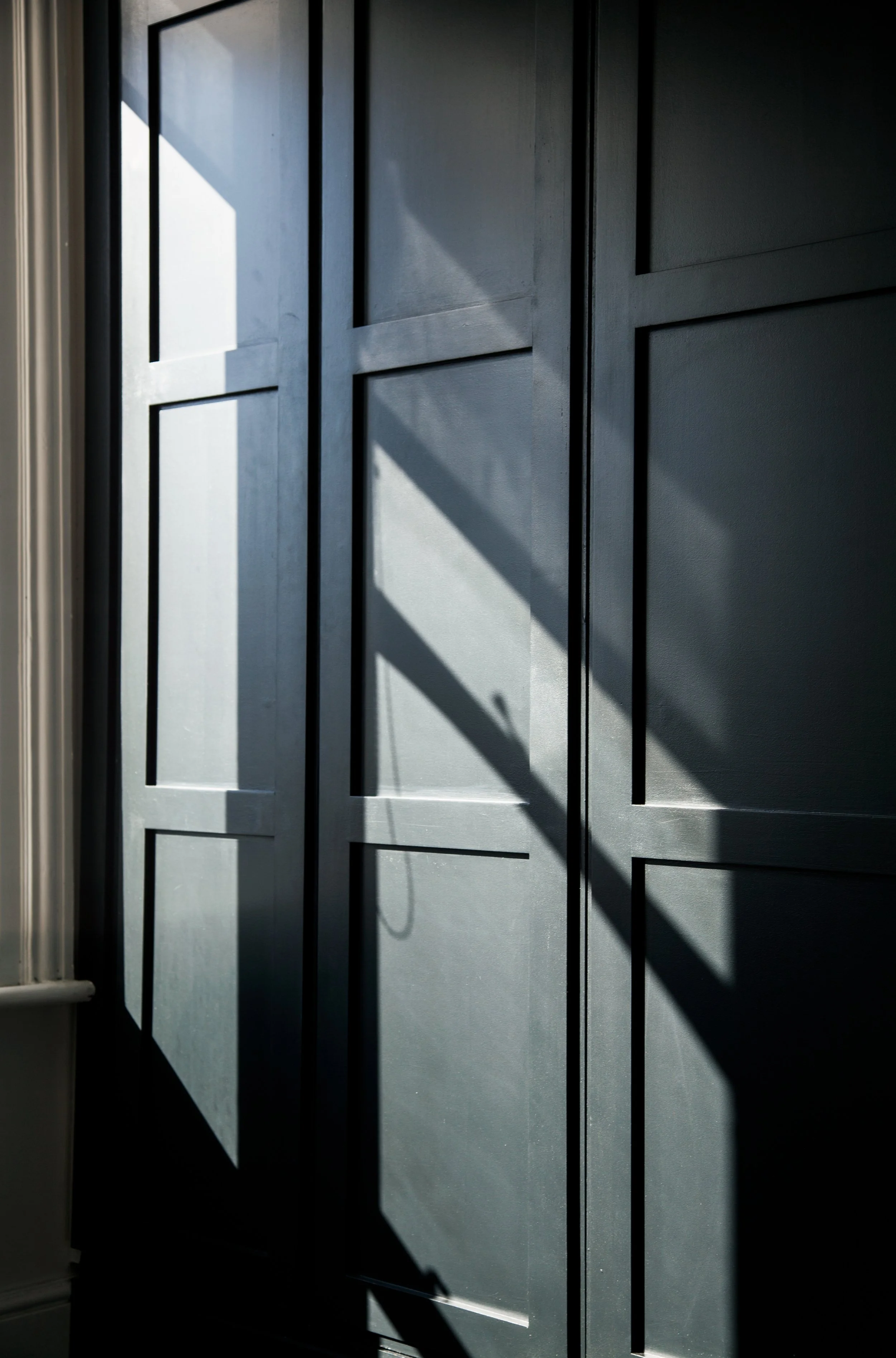 Sunlight casting shadows on a blue paneled door.